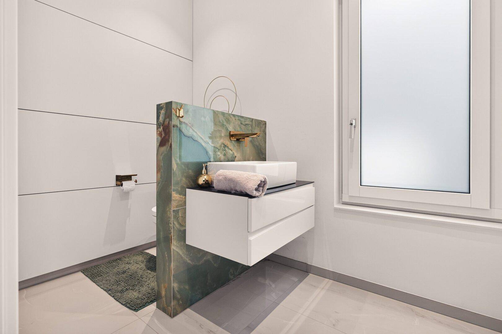Modernes Gäste-WC mit einzigartigem grünen Marmorwaschtisch, weißem Waschbecken und Fenster.