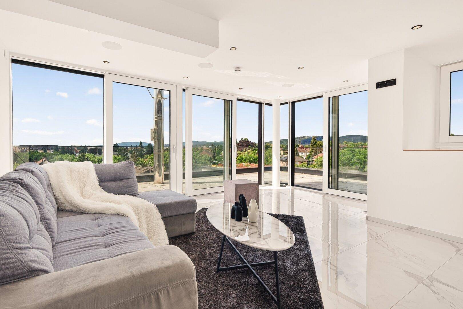 Großzügiges Wohnzimmer mit Marmorfliesen, bequemer Couch und Panoramafenstern.