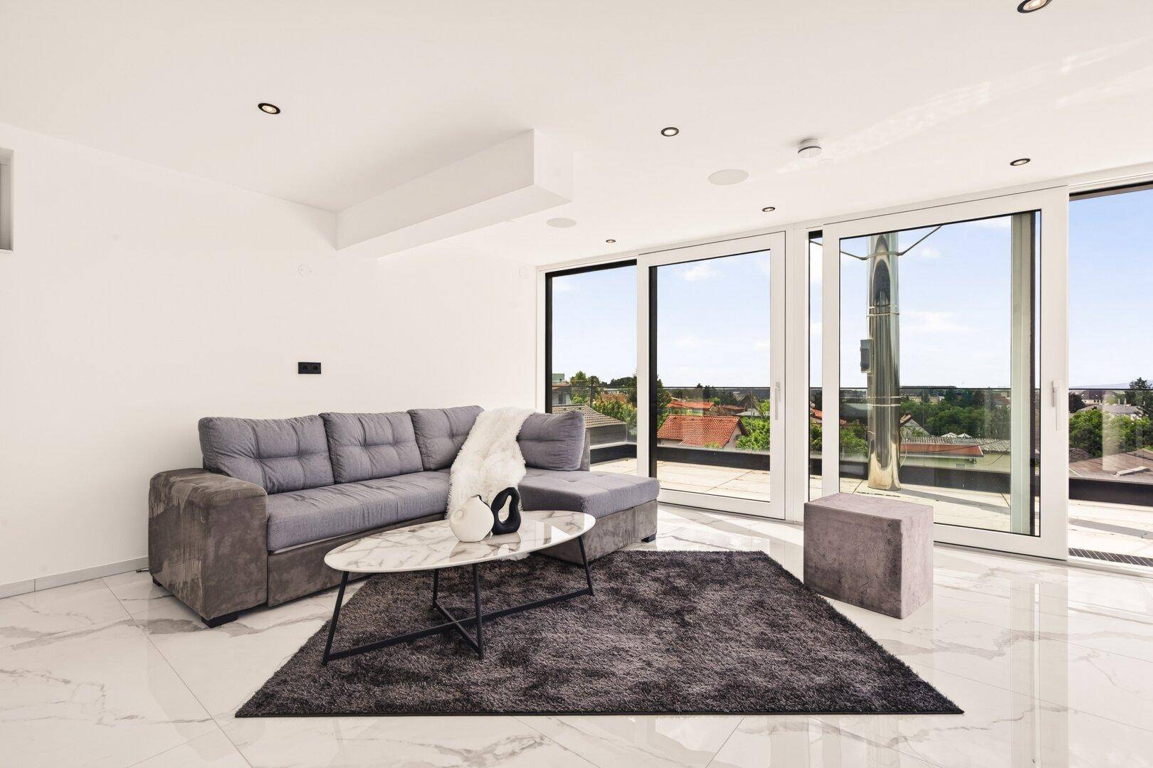 Helles Wohnzimmer mit Marmorfliesen, moderner Couch und weitem Ausblick.
