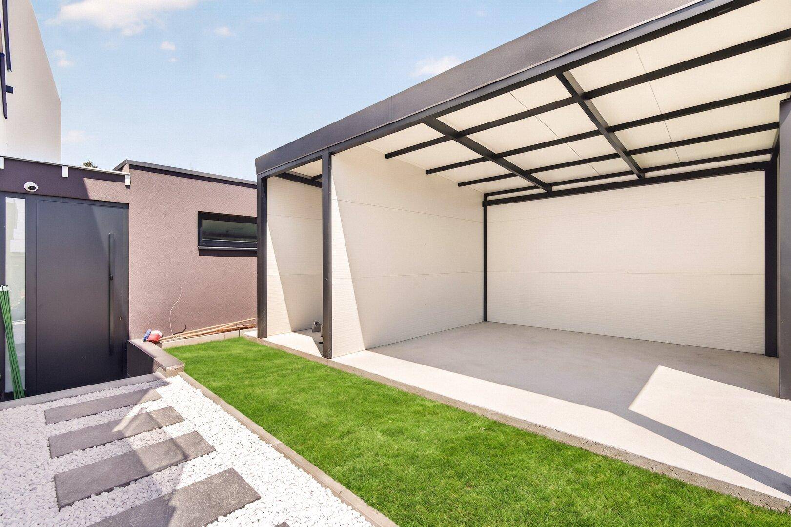 Moderner Carport mit offenem Design und angrenzender Grünfläche.