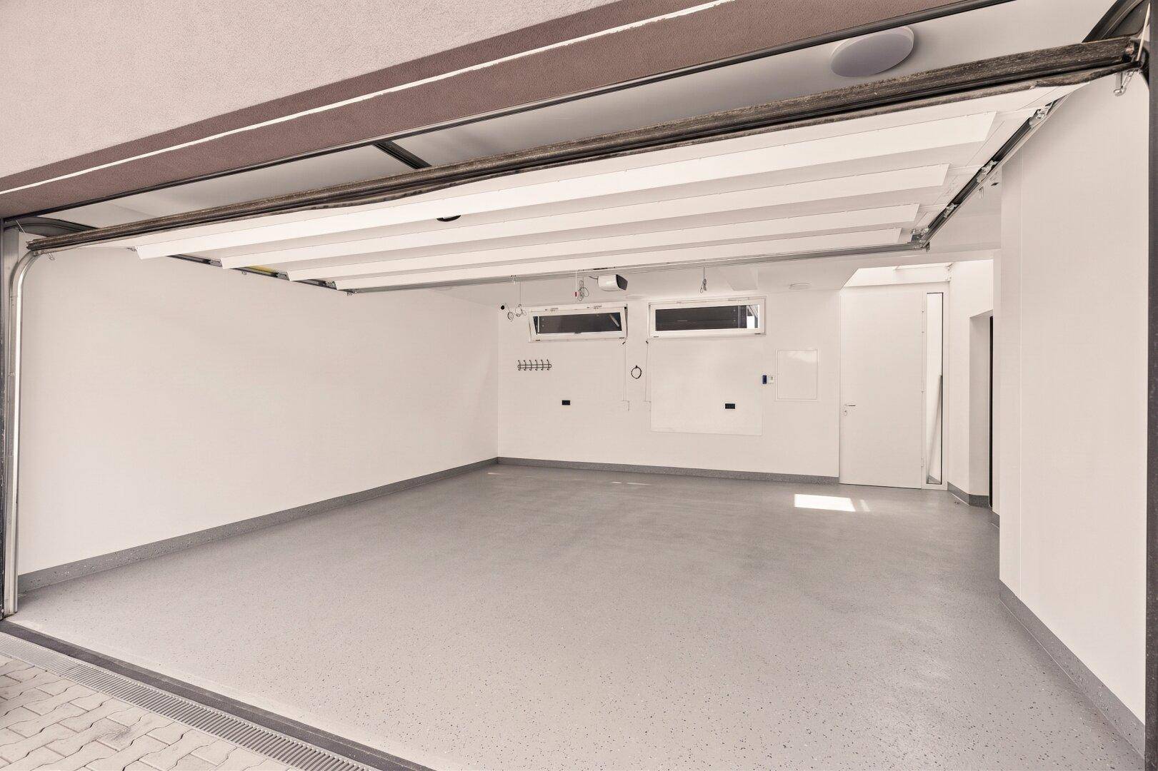 Geräumige Garage mit sauberem Boden und Fenstern für Tageslicht.