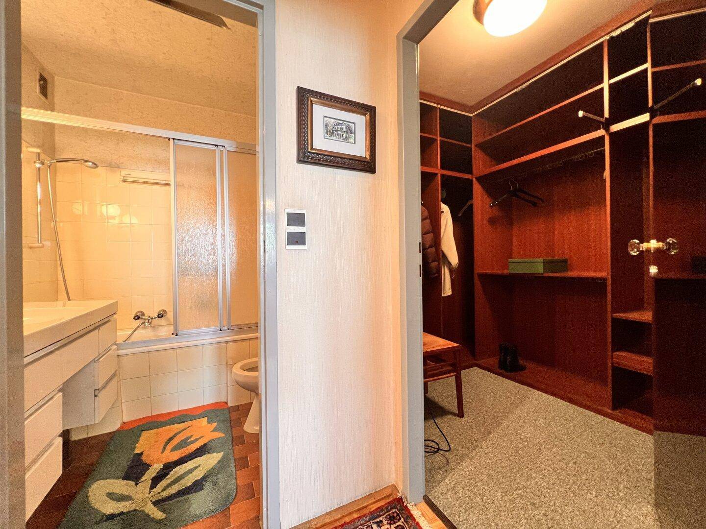 Blick auf ein Badezimmer mit Badewanne und eine angrenzende begehbare Garderobe.