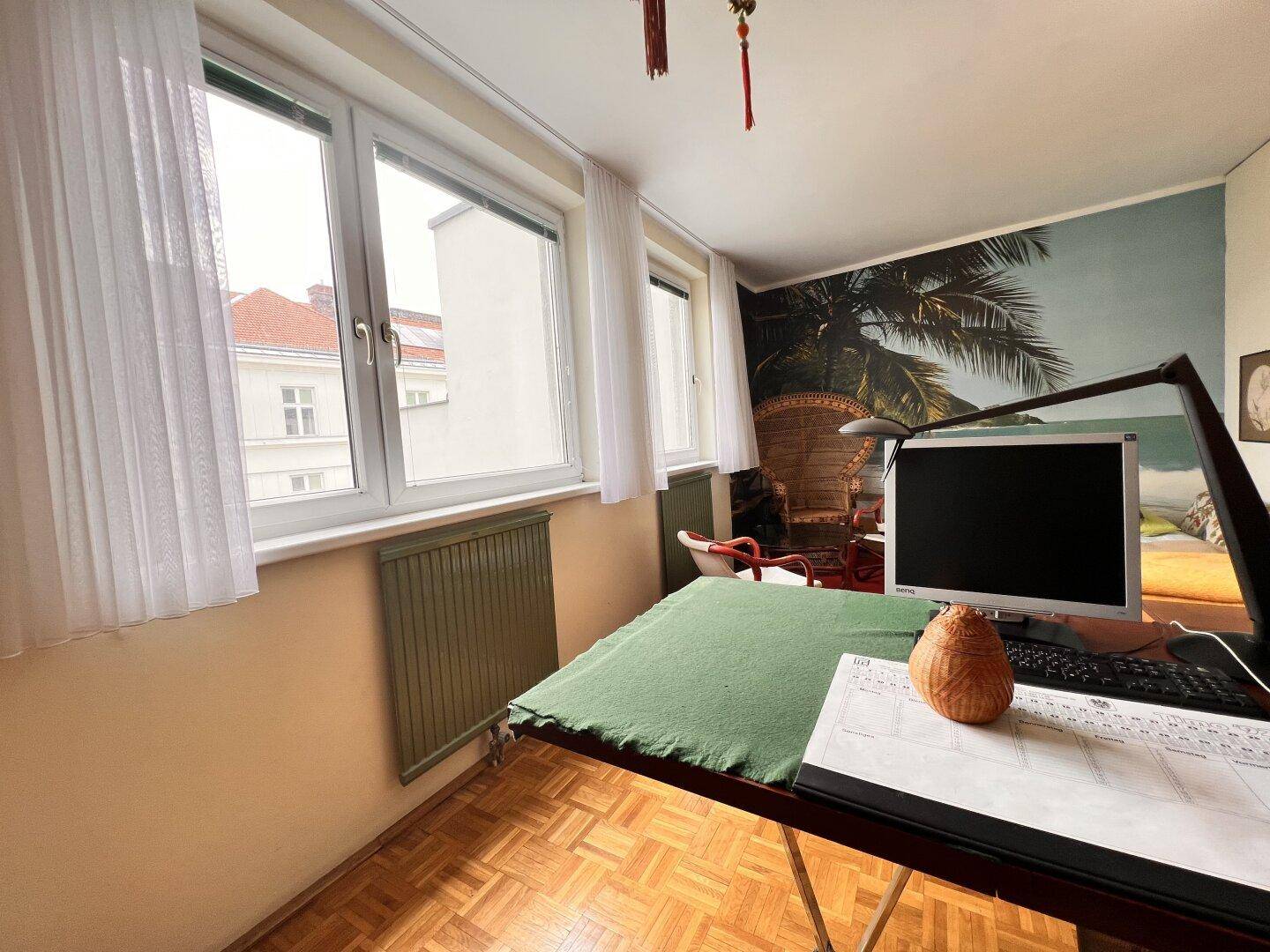 Detailansicht des Arbeitsplatzes im Büro mit Schreibtisch, Computer und Blick aus dem Fenster.