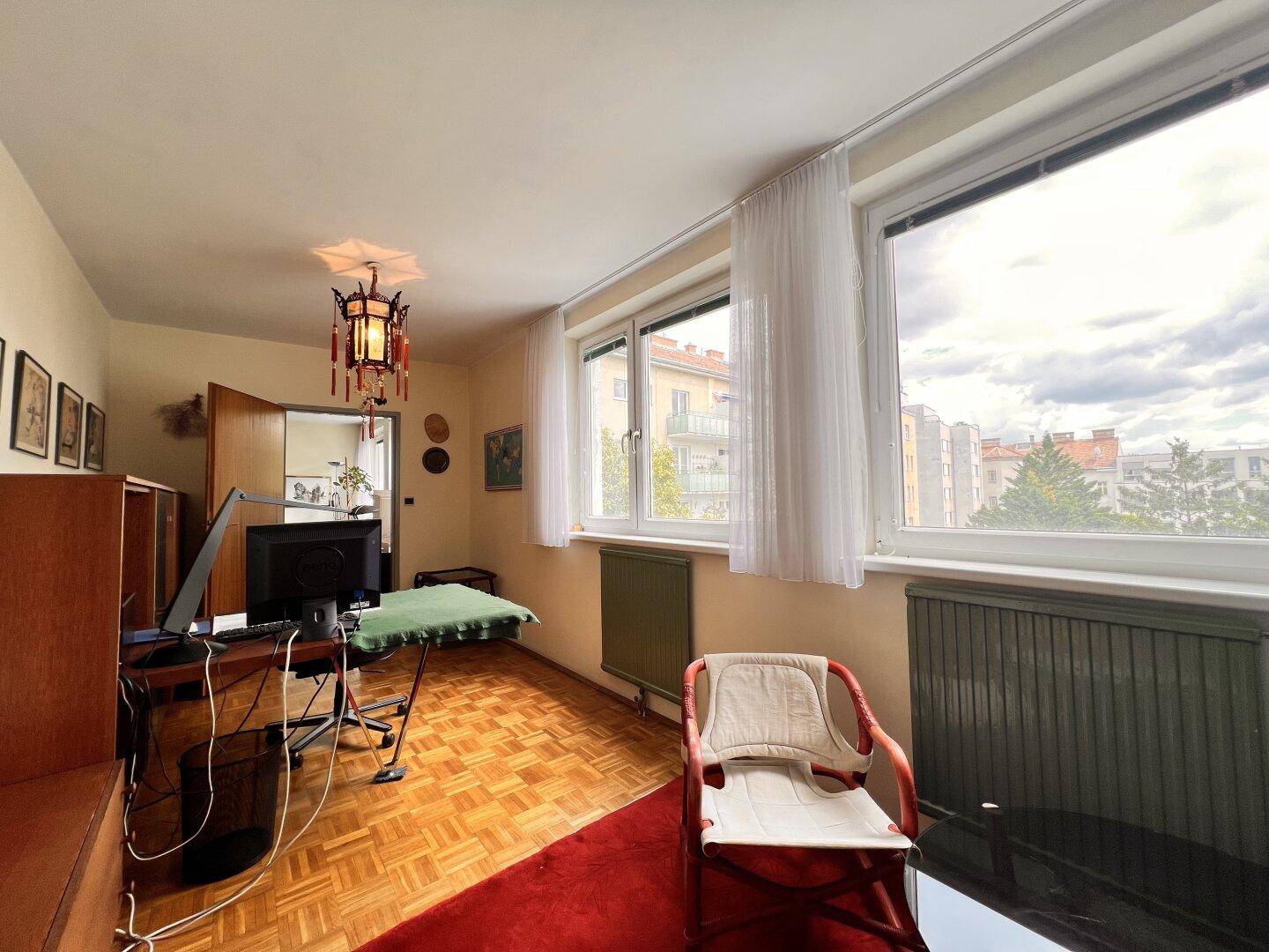 Arbeitszimmer mit Parkettboden, Schreibtisch und Fenster, das einen Blick auf die Umgebung bietet.
