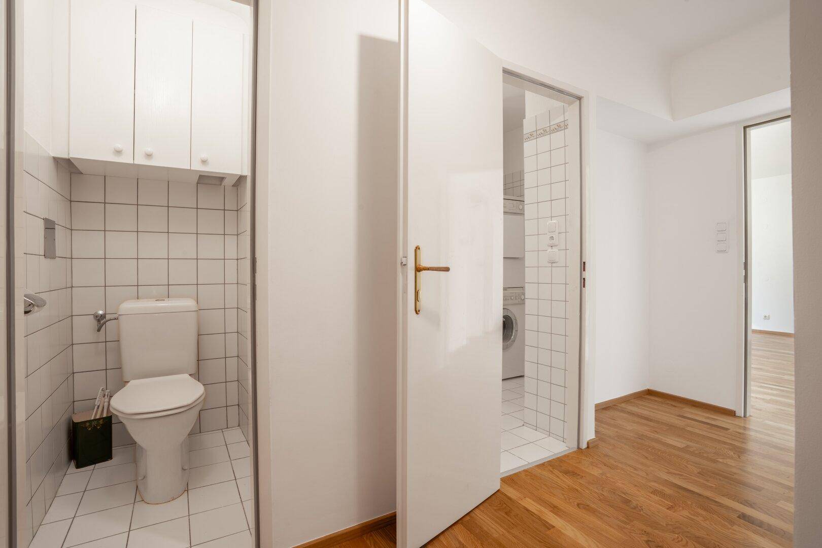 Heller Flur mit Parkettboden und Zugang zu separatem WC und Badezimmer, gut beleuchtet.