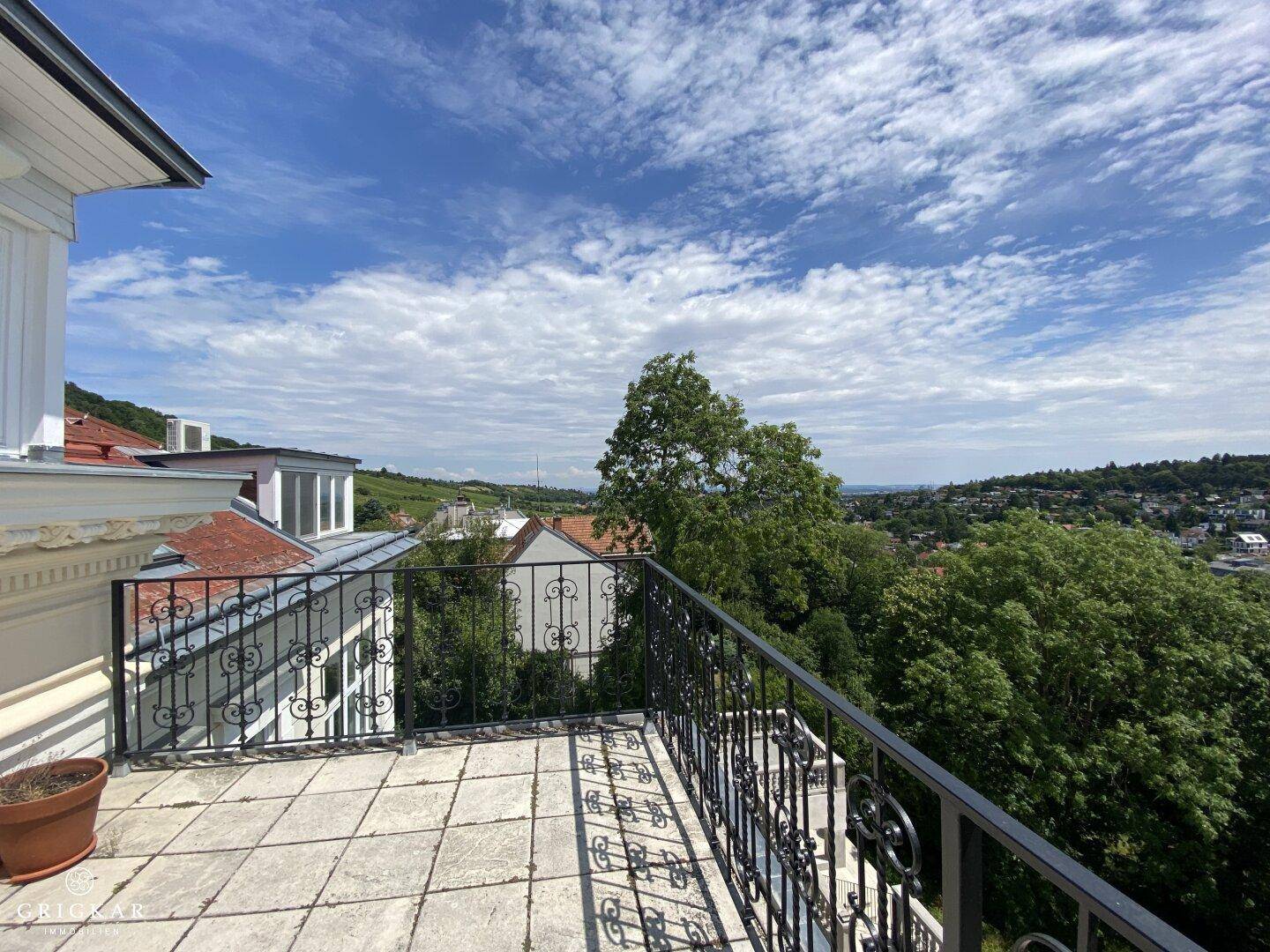 Große Terrasse mit Fliesenboden und schmiedeeisernem Geländer, bietet weiten Blick ins Grüne.