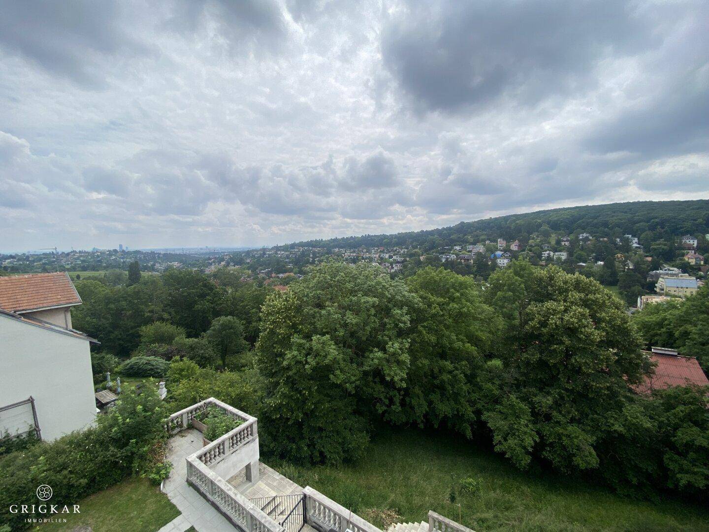 Weitläufiger Ausblick über eine grüne Landschaft mit Wohnbebauung und Stadtsilhouette.