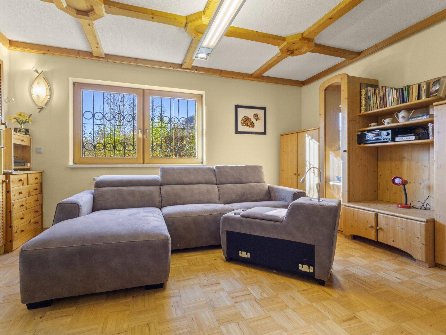 Gemütliches Wohnzimmer mit großem Sofa, Holzmöbeln und charakteristischer Holzbalkendecke.