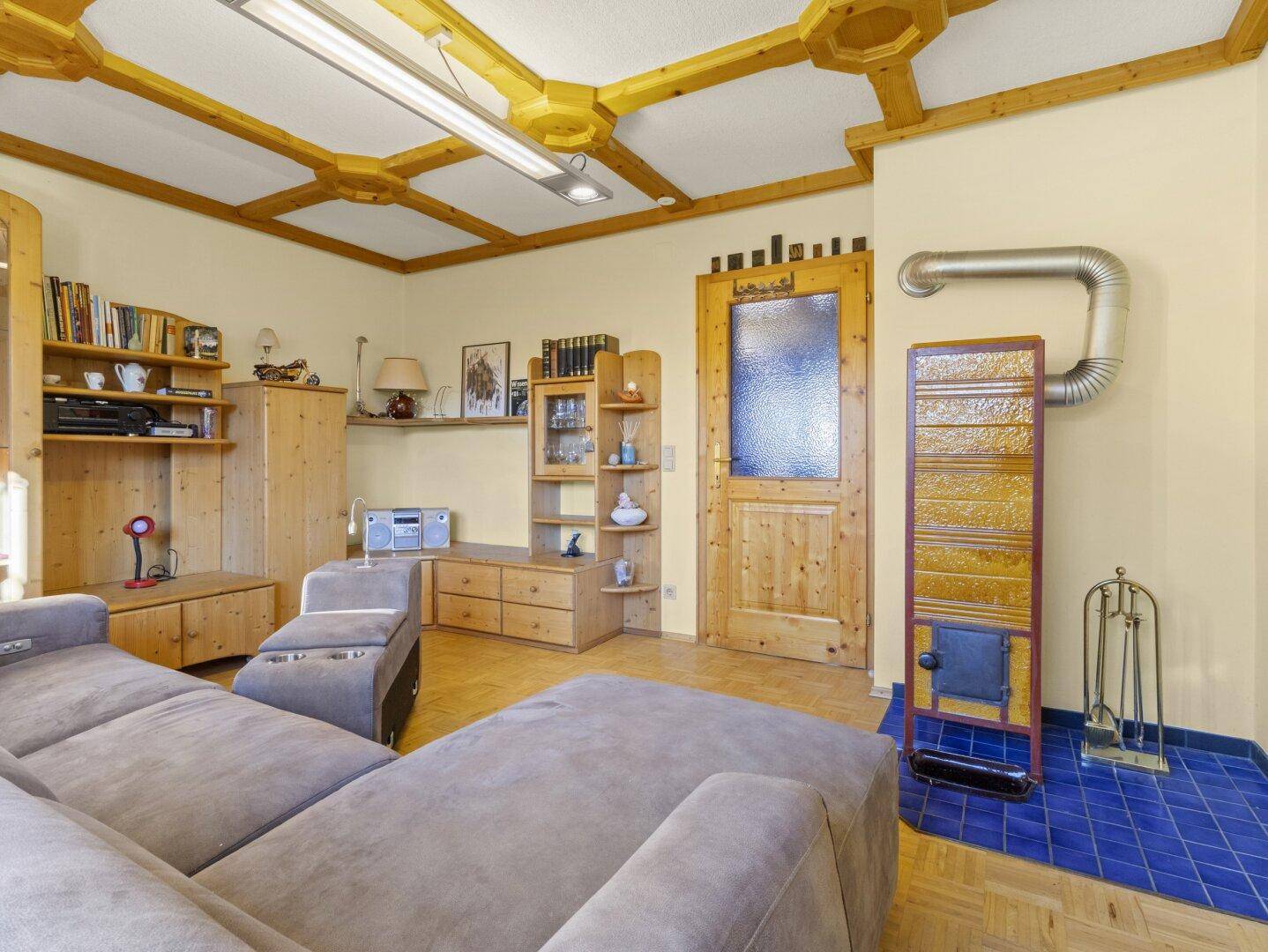 Wohnzimmer mit traditionellem Kachelofen, Holzbalkendecke und rustikalen Möbeln.