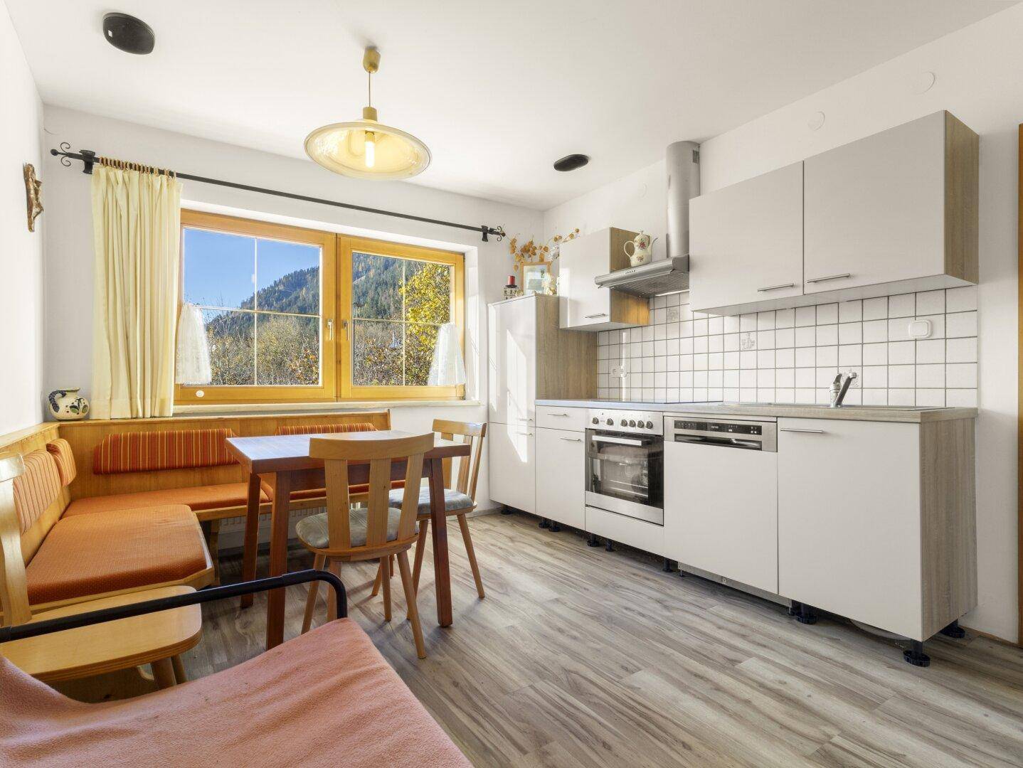 Moderne Küche mit hellem Holzdekor, Essbereich und Fenster mit Bergblick.