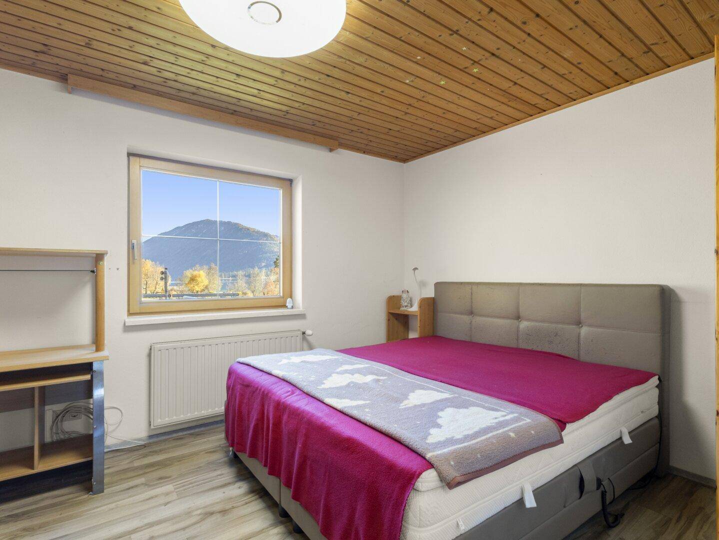 Schlafzimmer mit Doppelbett, Schreibtisch und Fenster mit Bergblick.