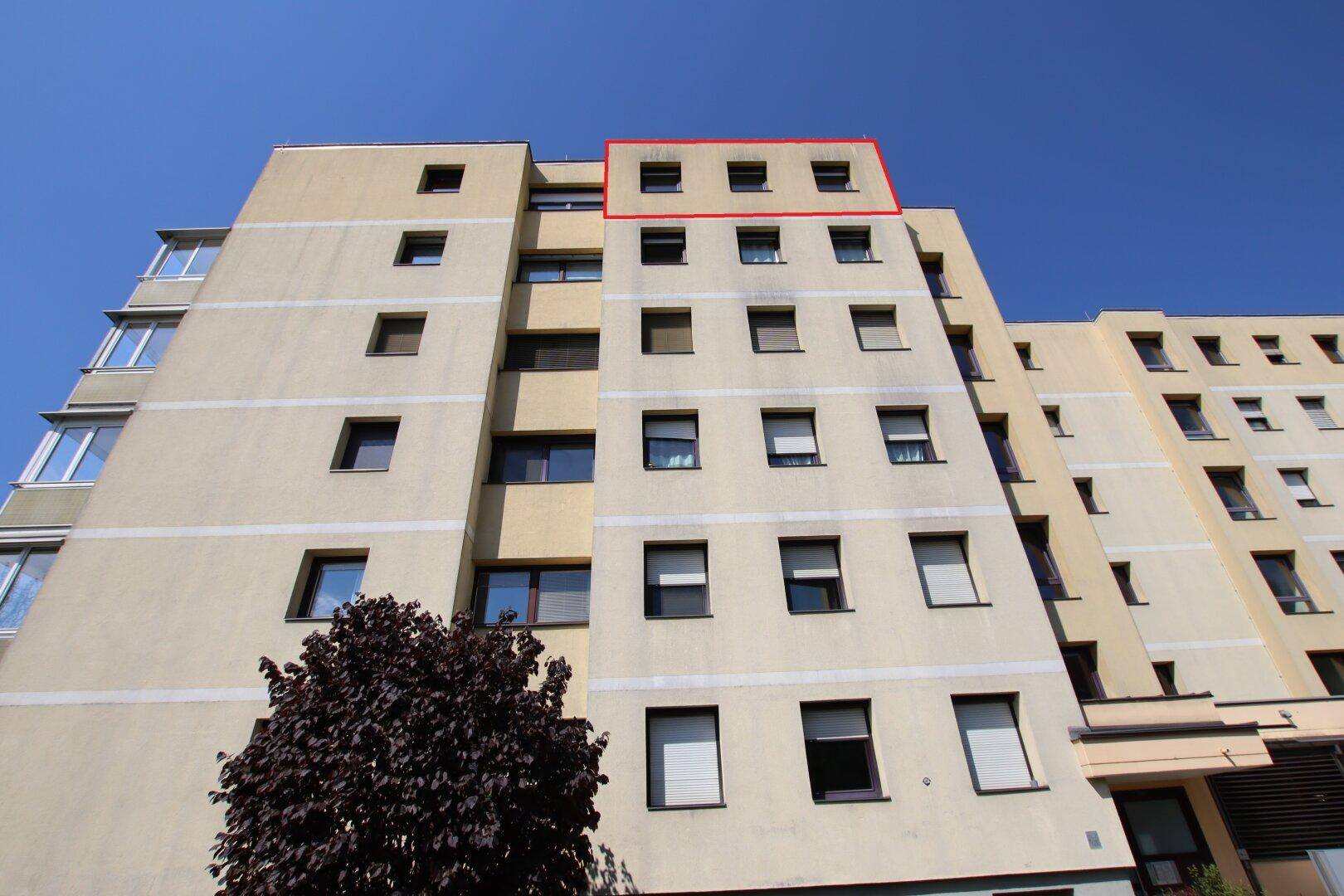 Ansicht eines modernen Wohngebäudes mit beiger Fassade und vielen Fenstern.