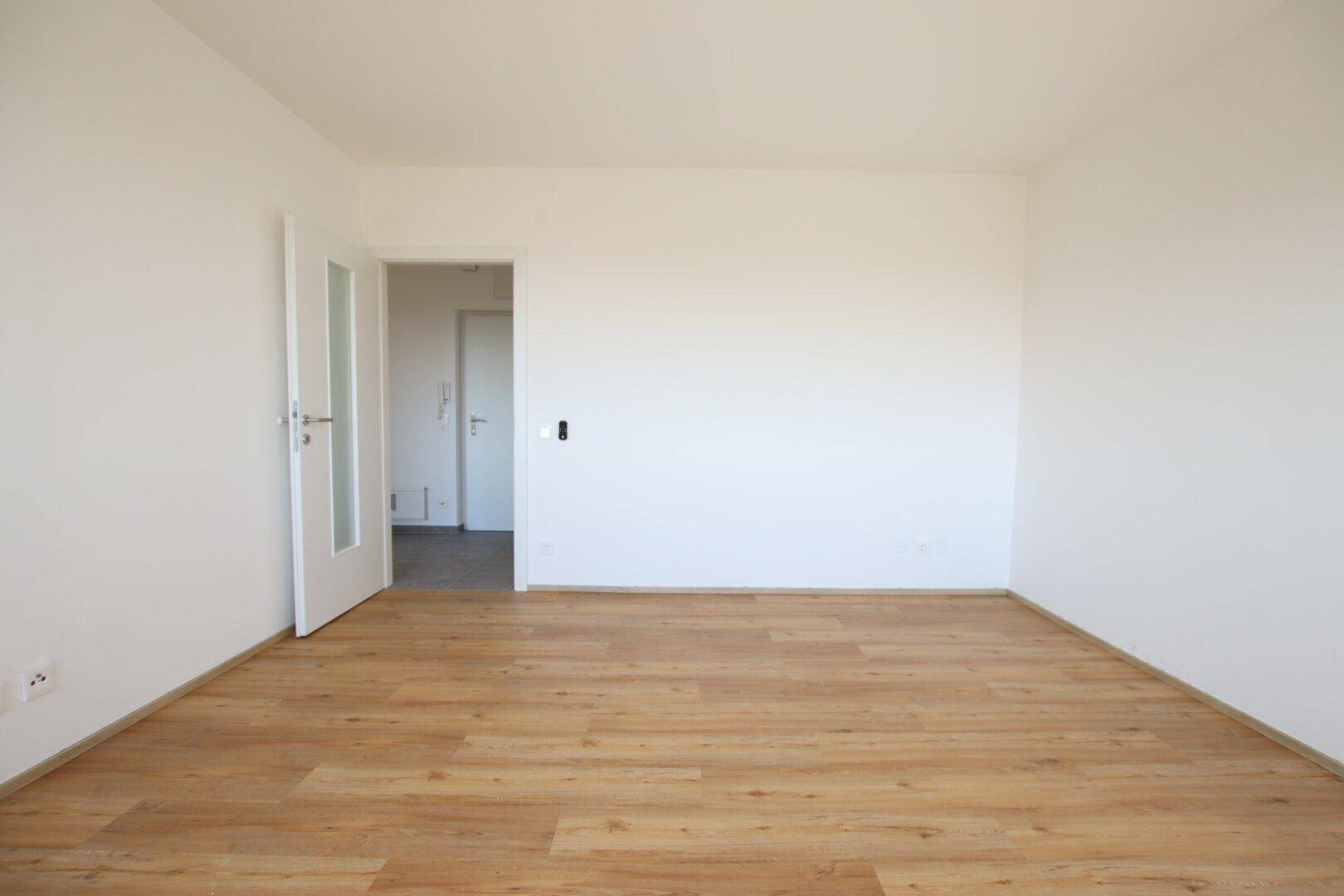 Geräumiges Zimmer mit hellem Laminatboden und weiß gestrichenen Wänden, bereit zur Einrichtung.