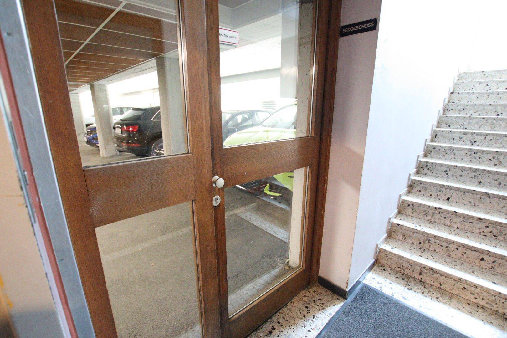 Eingangsbereich mit Holzglastür und Treppe, die zur Tiefgarage führt.
