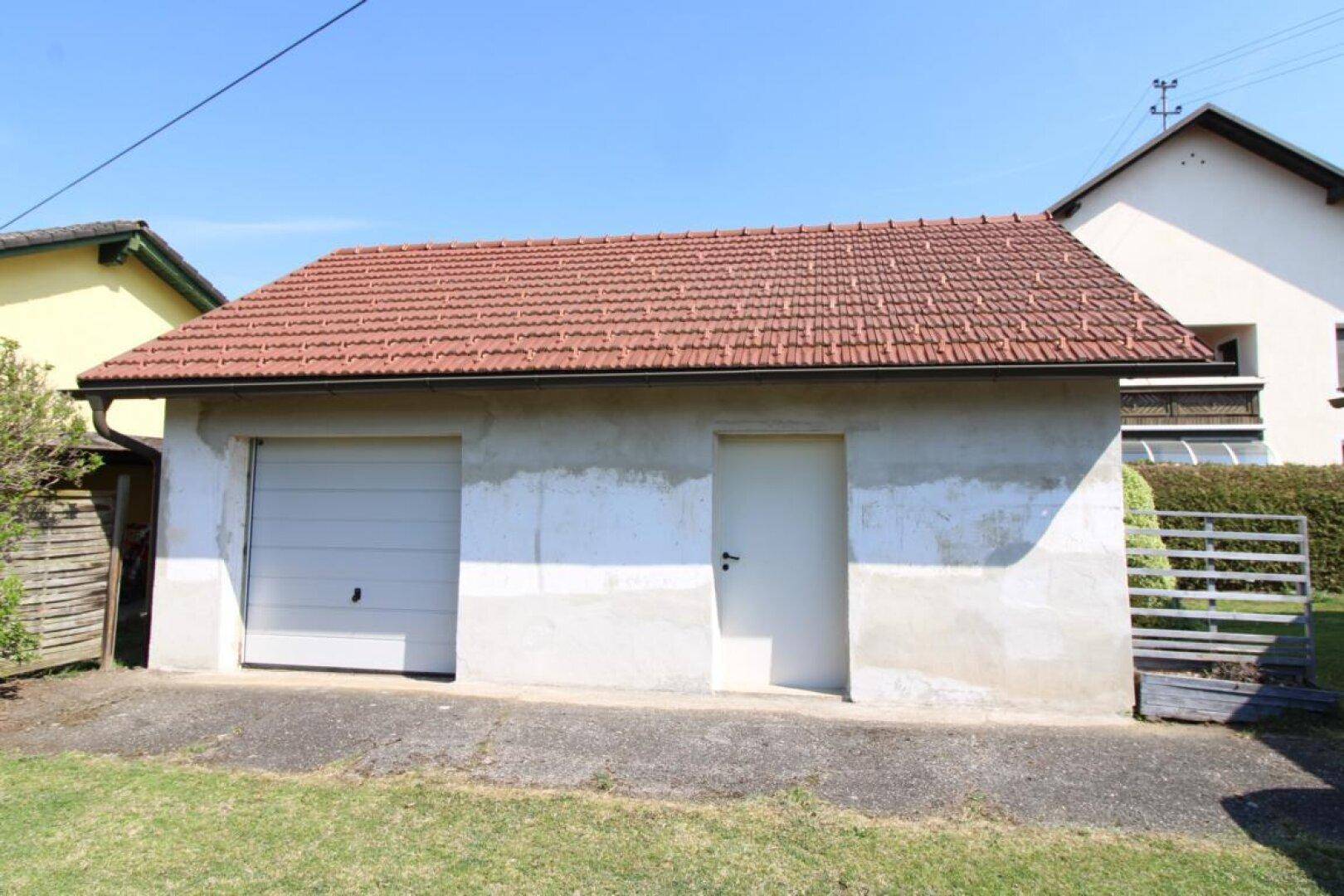 Separate Garage mit einem Garagentor und einer zusätzlichen Eingangstür.