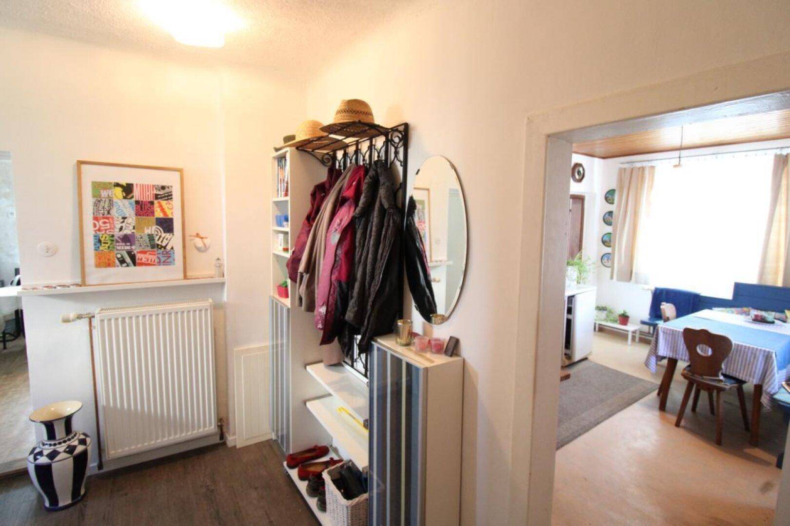Heller Flur mit Garderobe, Spiegel und Zugang zu weiteren Räumen, mit Laminatboden.