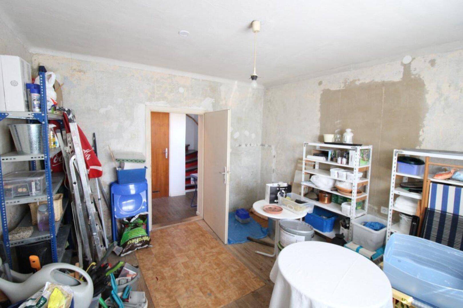 Abstellraum mit Regalen und verschiedenen Gegenständen, die Wände sind renovierungsbedürftig.