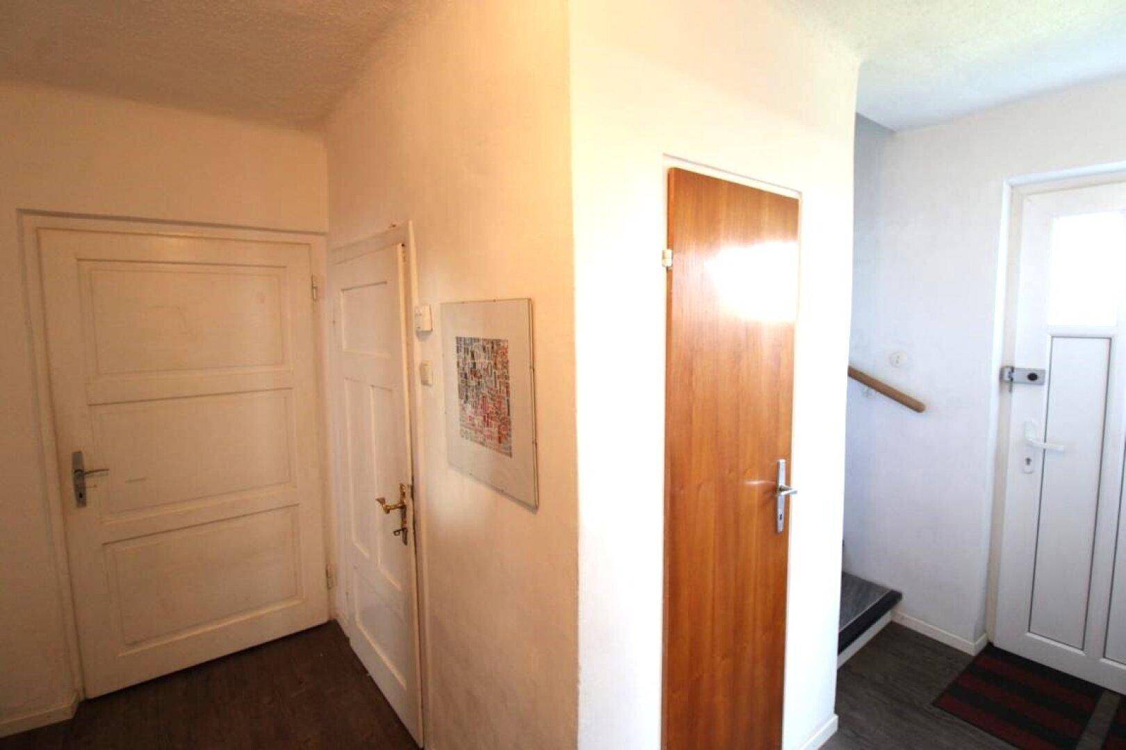 Flur mit verschiedenen Holztüren und einem Eingangsbereich mit Treppe.
