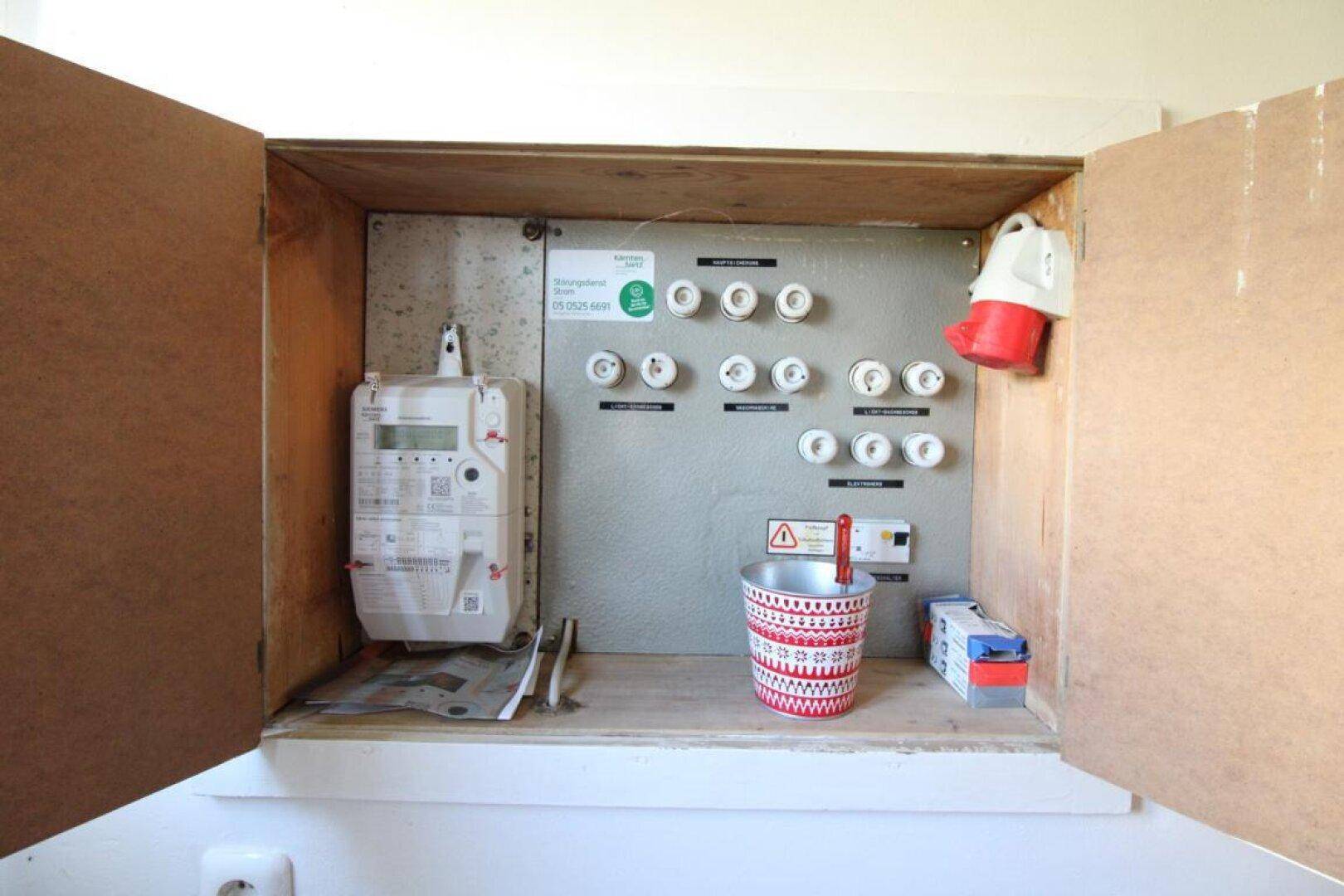 Elektrischer Sicherungskasten und Zähler in einem Holzschrank, wichtige Installationen.