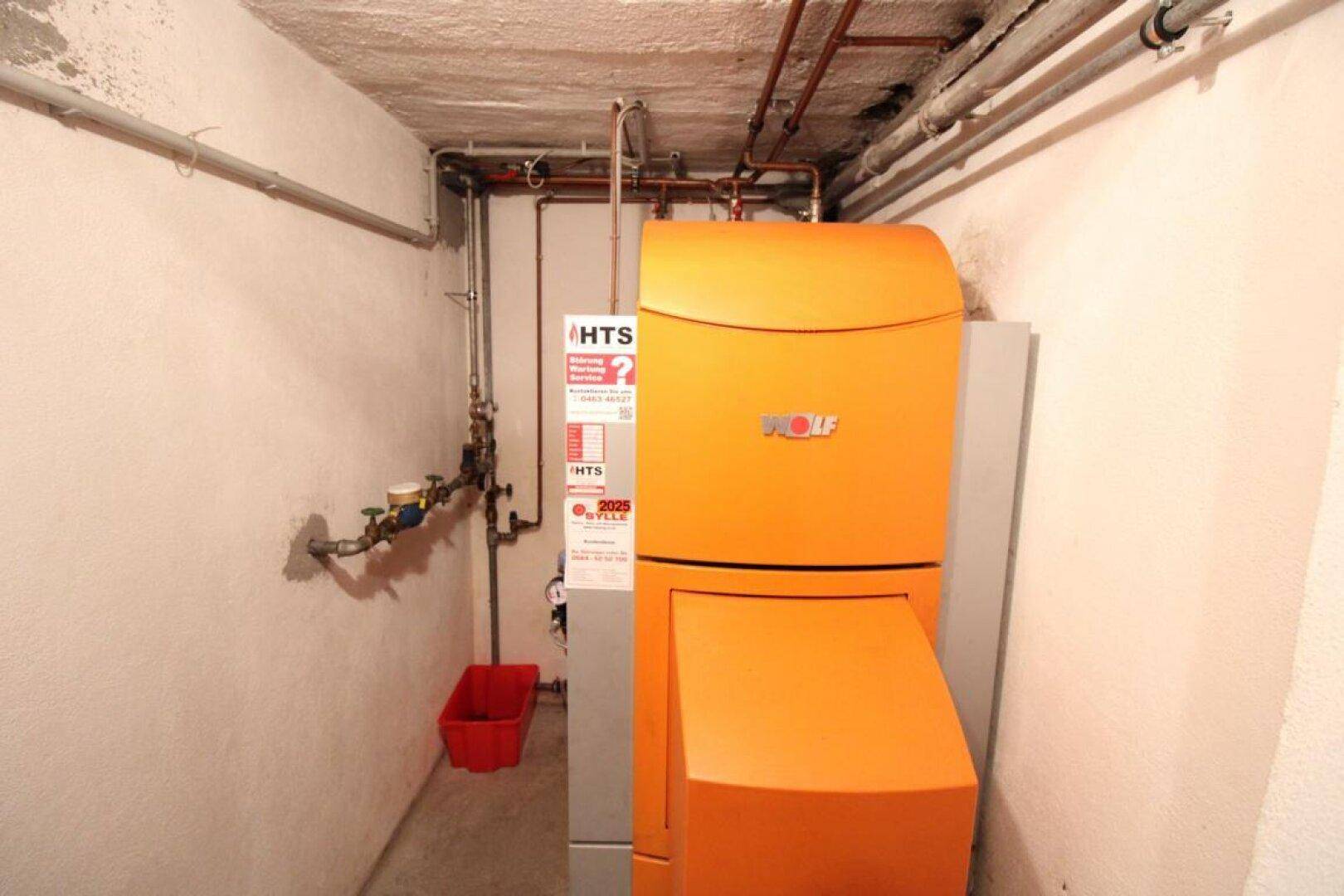 Heizungsraum im Keller mit moderner Wolf-Heizanlage und sichtbaren Installationen.