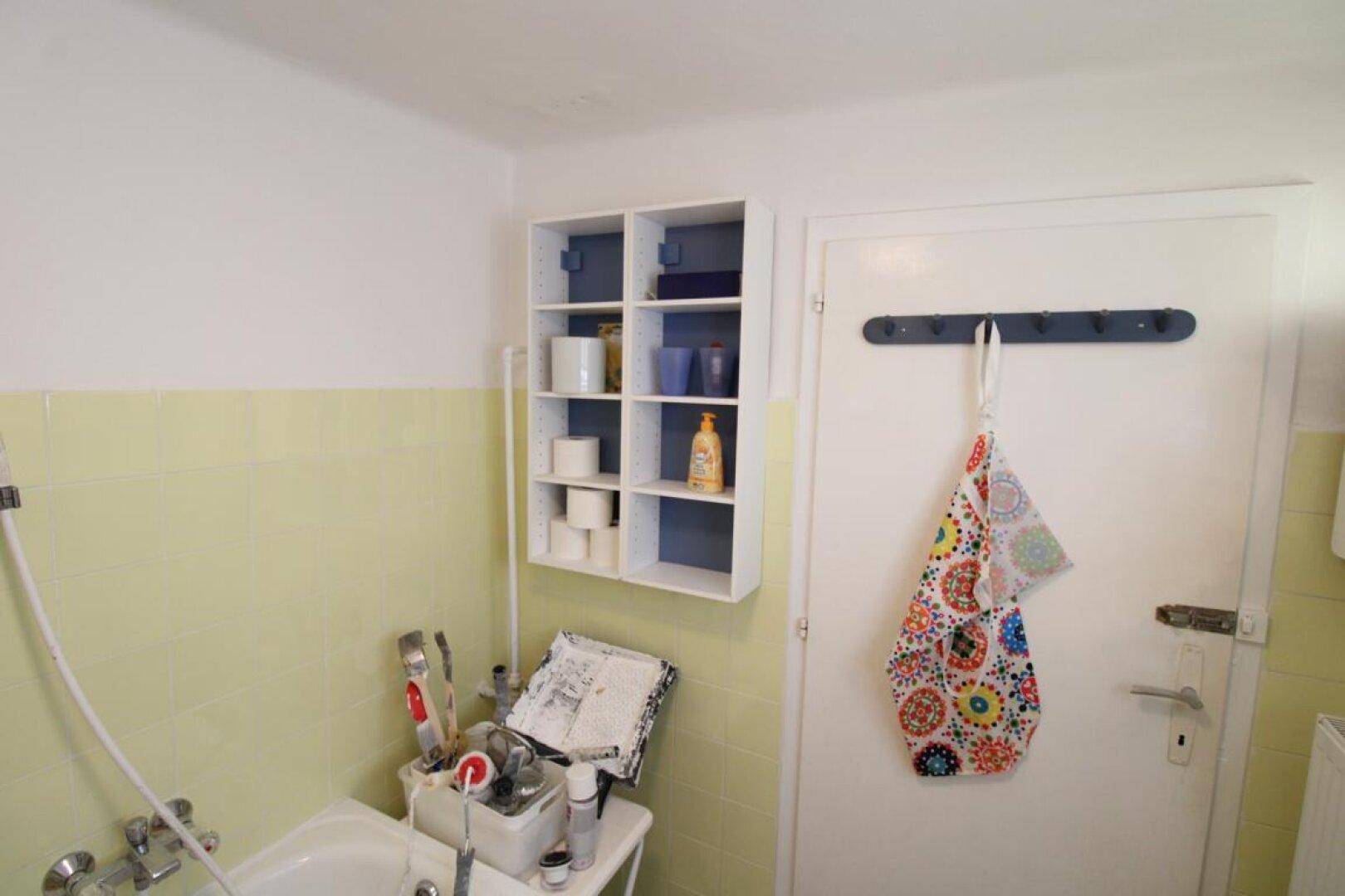 Badezimmer mit Waschbecken, Duschschlauch und Ablageflächen, in funktionaler Gestaltung.