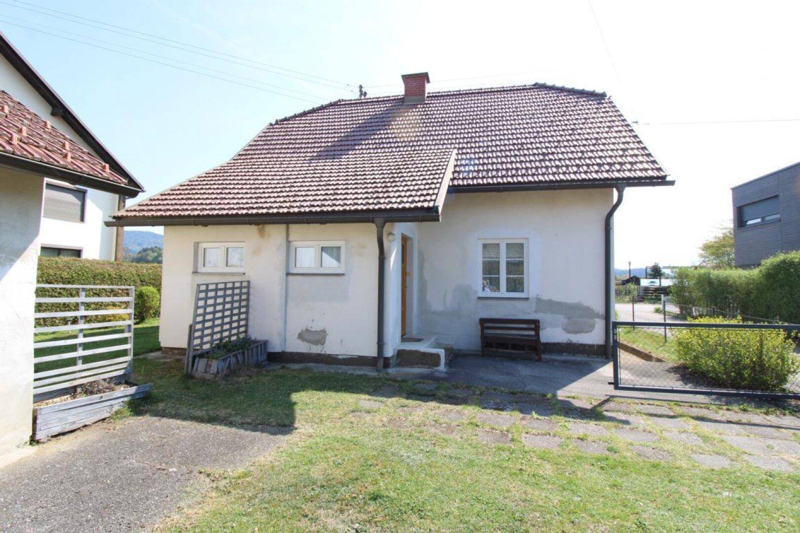 Vorderseite des Hauses mit einem kleinen gepflasterten Bereich und einer Rasenfläche.
