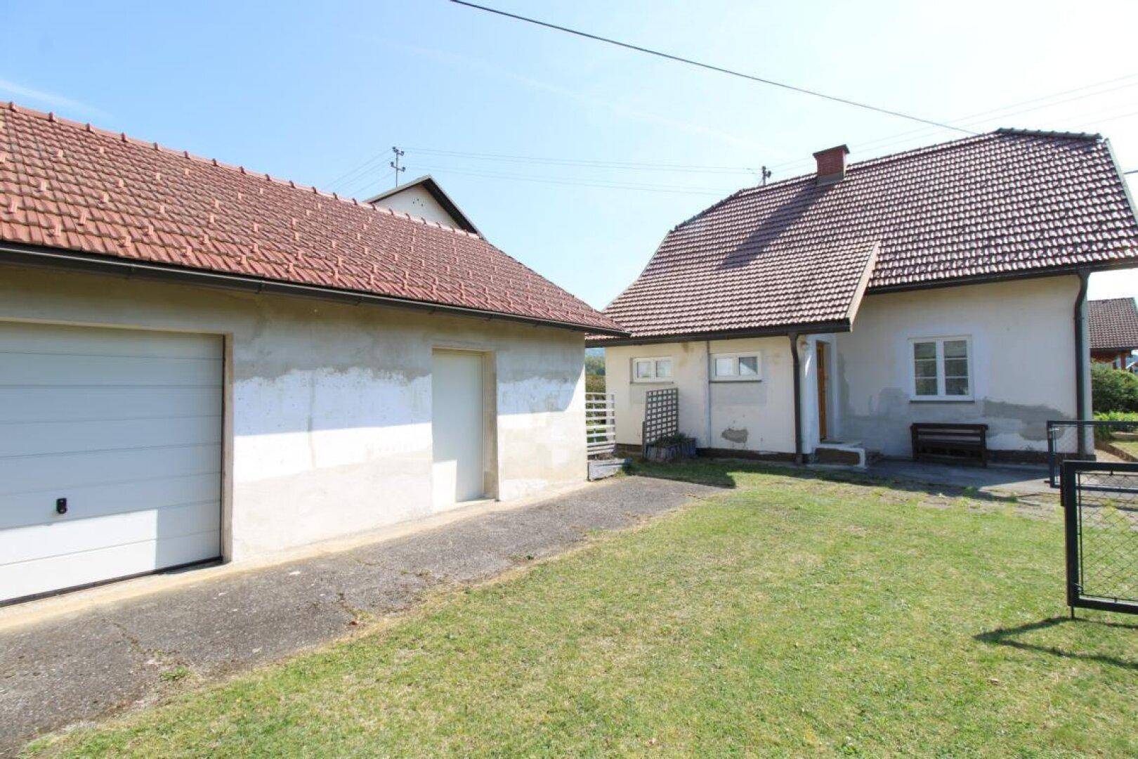 Gesamtansicht des Hauses und einer separaten Garage mit Rasenfläche und Einfahrt.