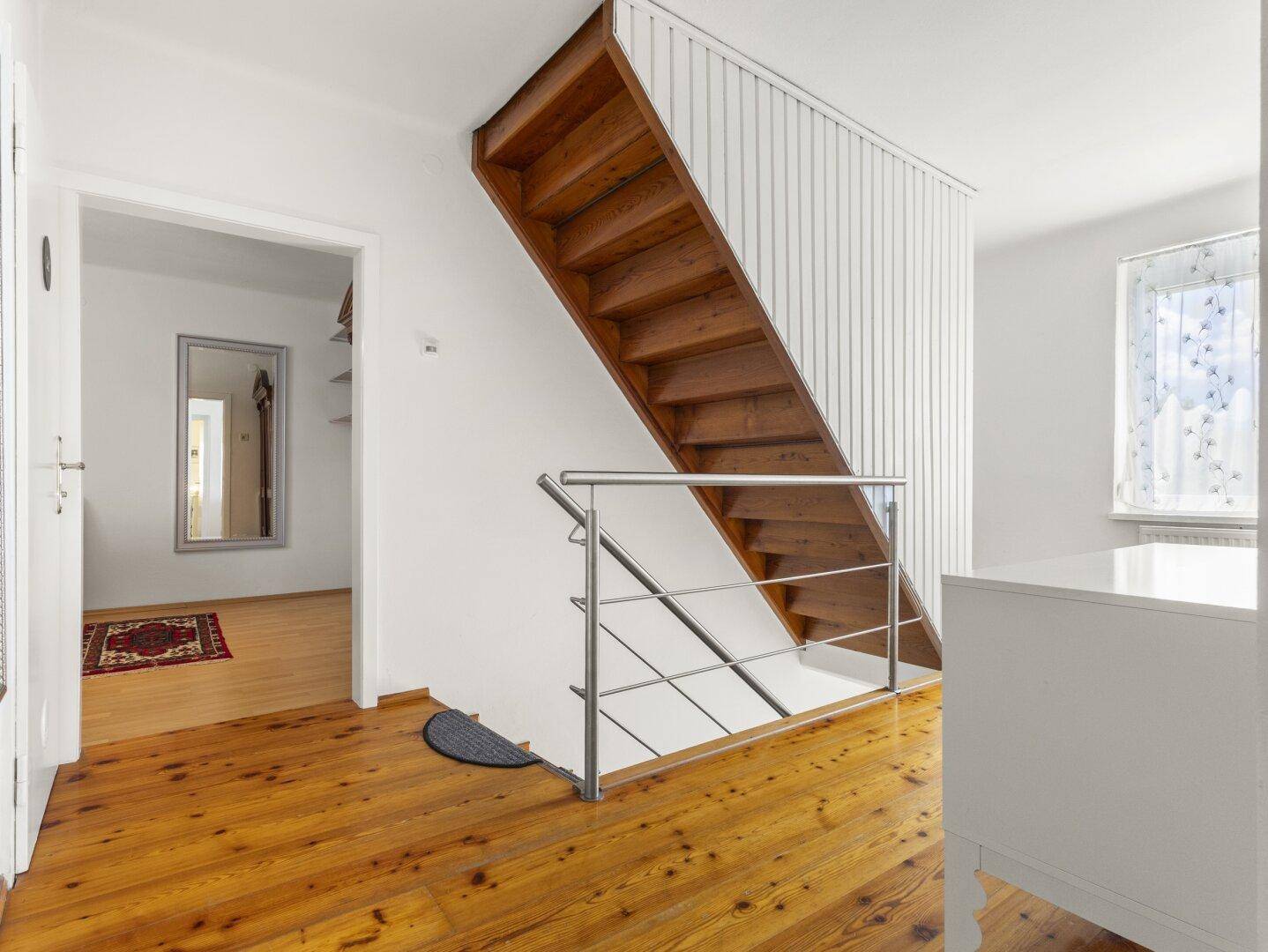 Oberer Flurbereich mit Holztreppe, Holzboden und Zugang zu weiteren Räumen.