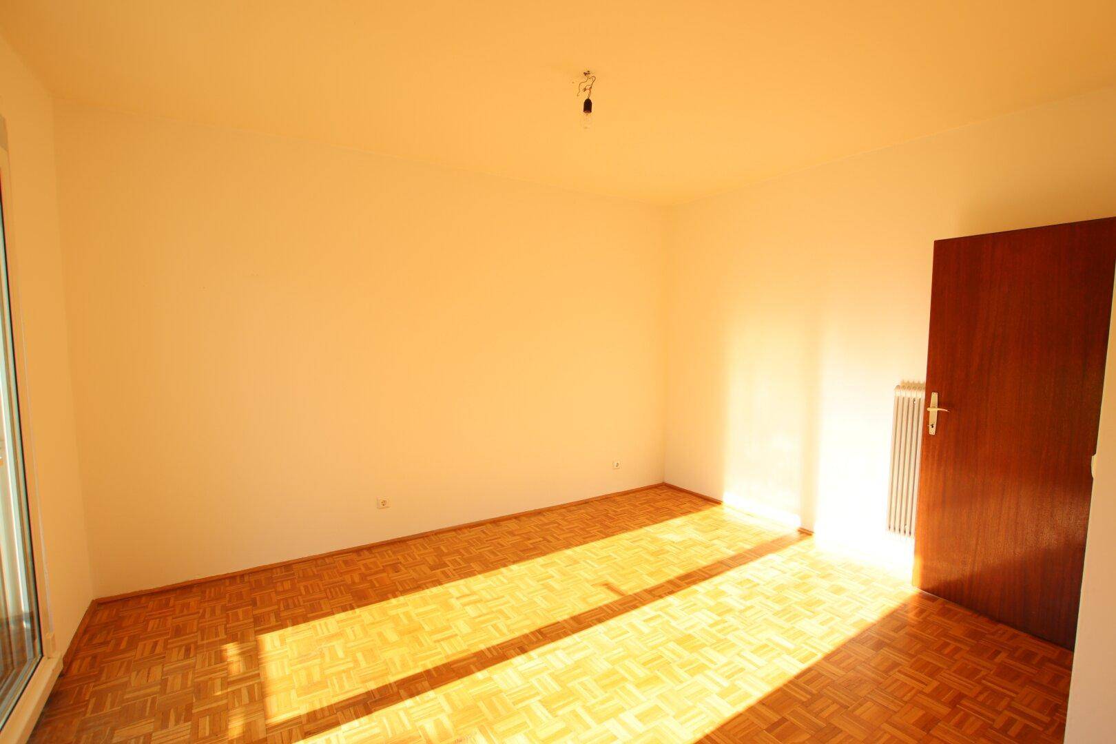 Sonniger Raum mit Parkettboden und viel Tageslicht, ideal als Wohn- oder Arbeitszimmer.