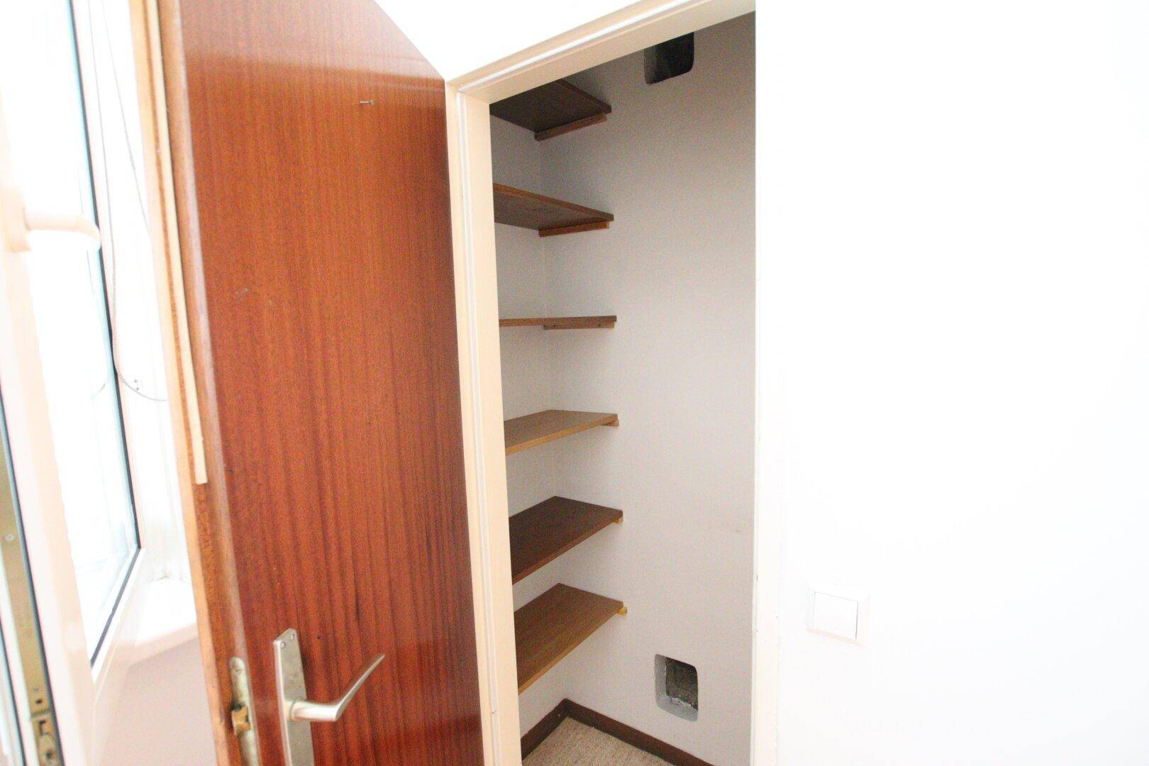Praktischer Abstellraum mit Holzregalen, ideal zur Aufbewahrung von Haushaltsgegenständen.