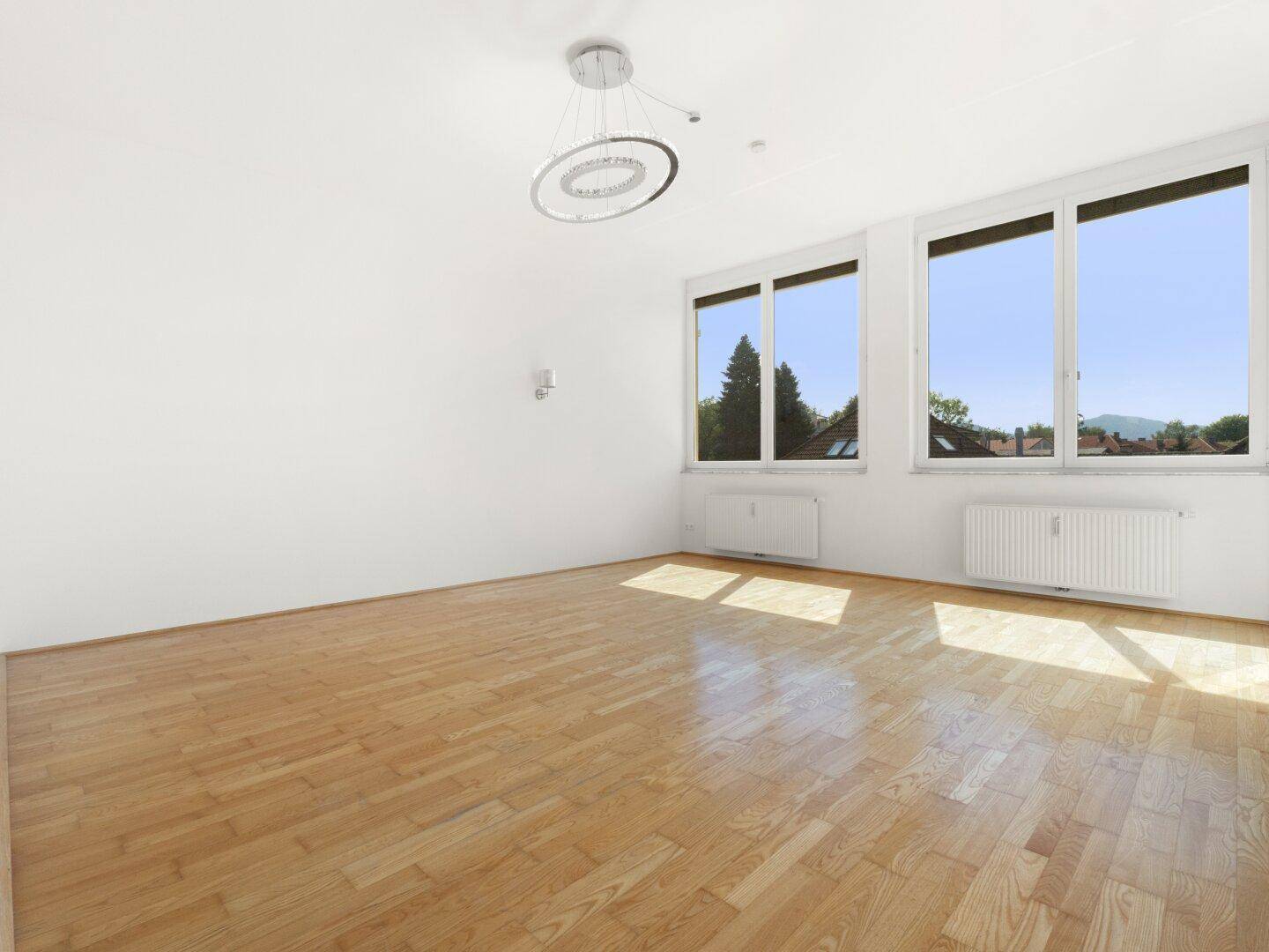Helles Wohnzimmer mit Parkettboden und weitem Ausblick durch die großen Fenster.