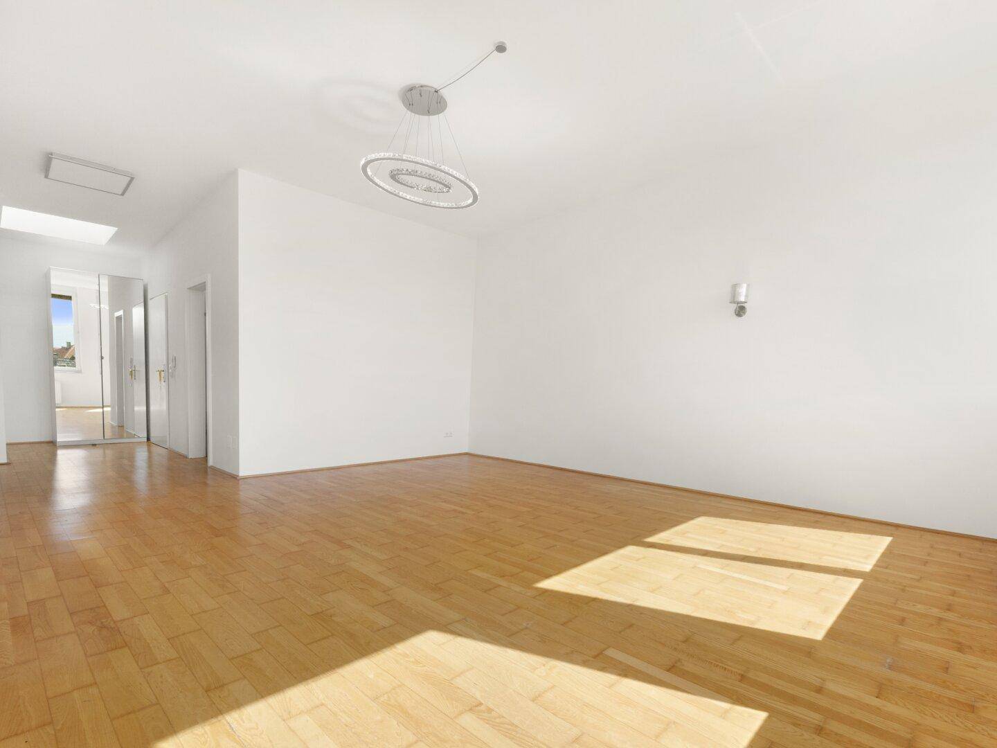 Geräumiges Wohnzimmer mit Parkettboden und viel Tageslicht, bereit für individuelle Gestaltung.