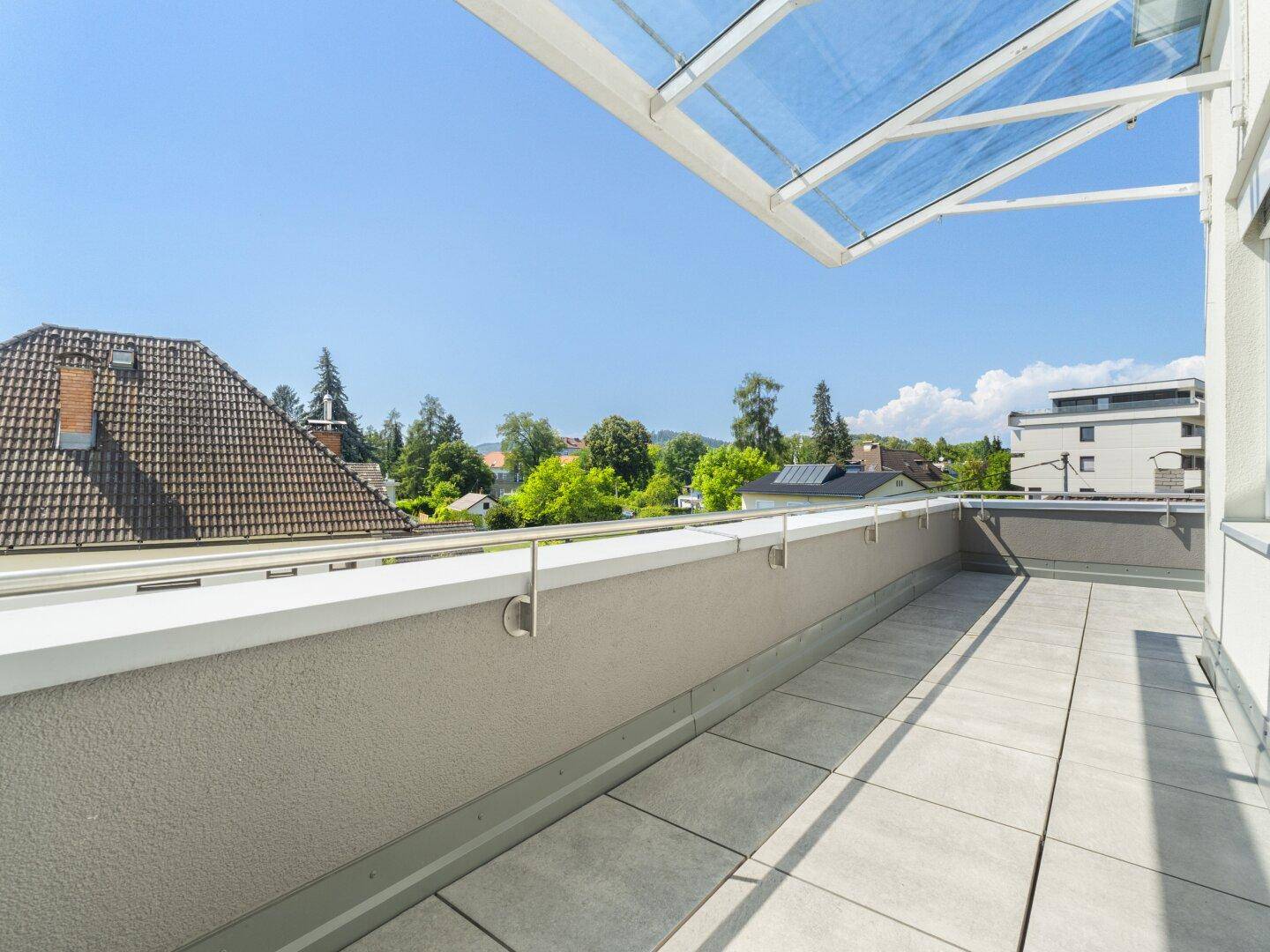 Große Dachterrasse mit Fliesenboden und schöner Aussicht, teilweise überdacht.