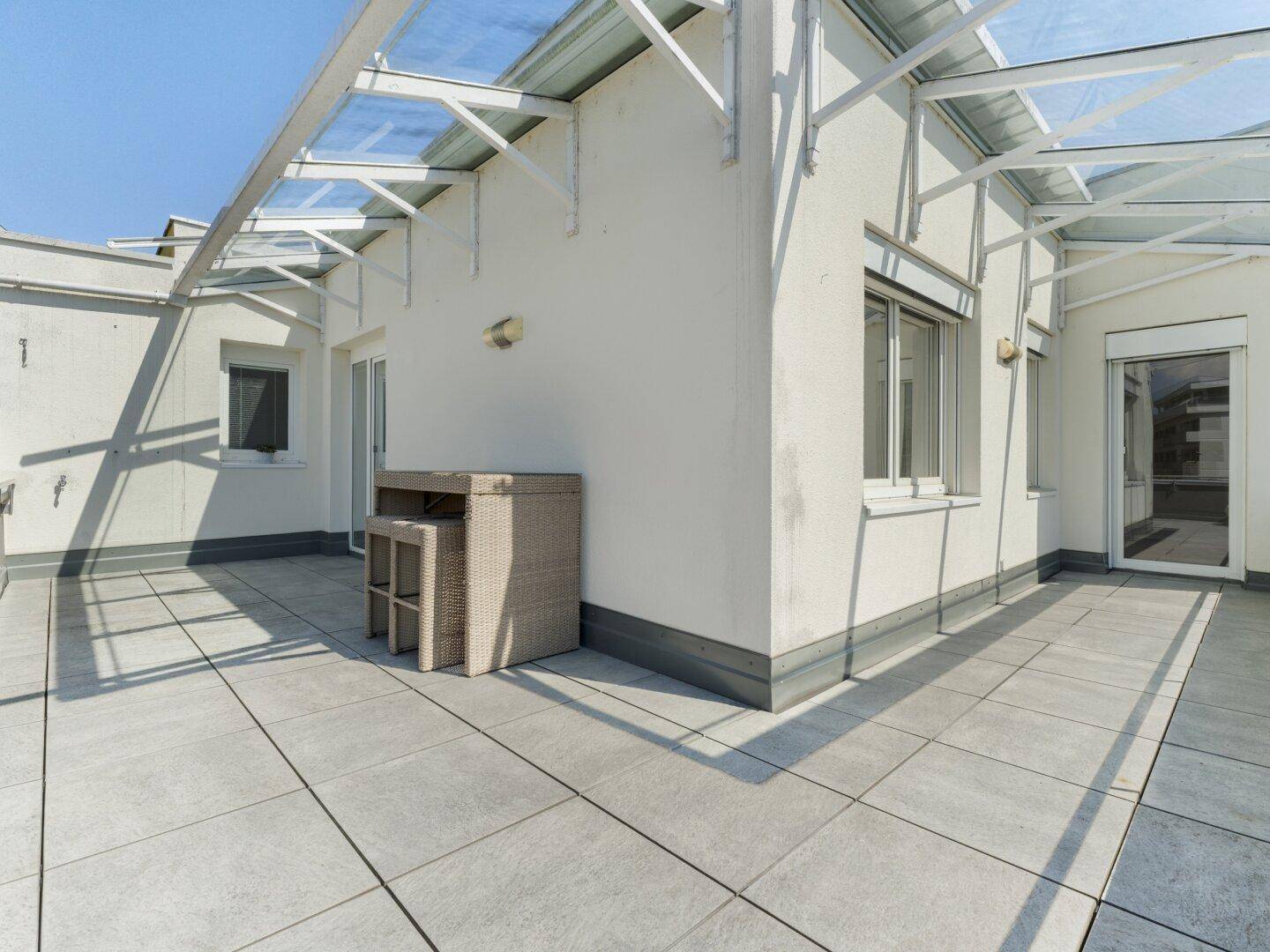 Geräumige Dachterrasse mit Sitzgelegenheiten und einer transparenten Überdachung.