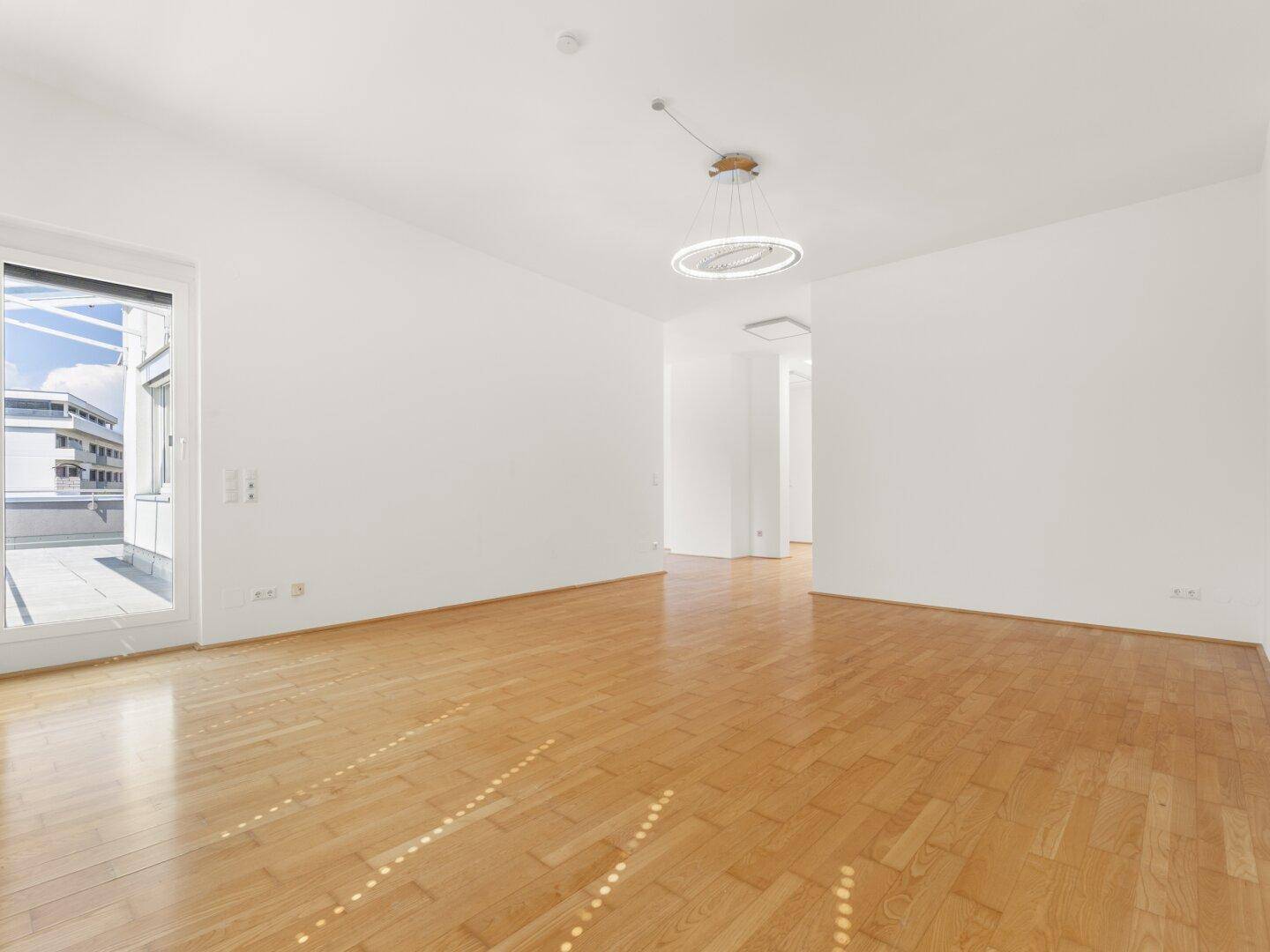 Helles Wohnzimmer mit Parkettboden und direktem Zugang zur großzügigen Dachterrasse.