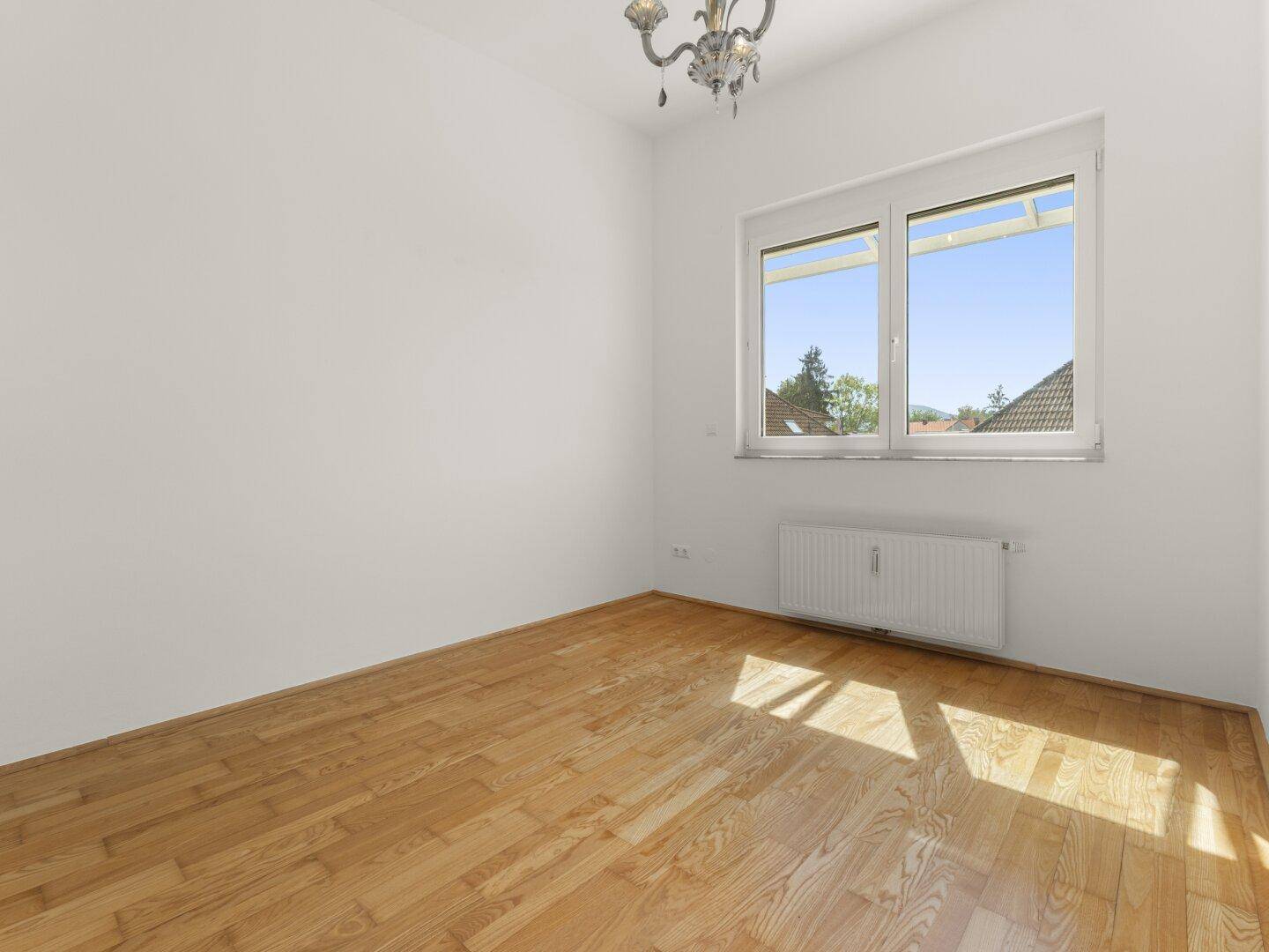 Schlafzimmer mit Parkettboden, großen Fenstern und einem eleganten Kronleuchter.