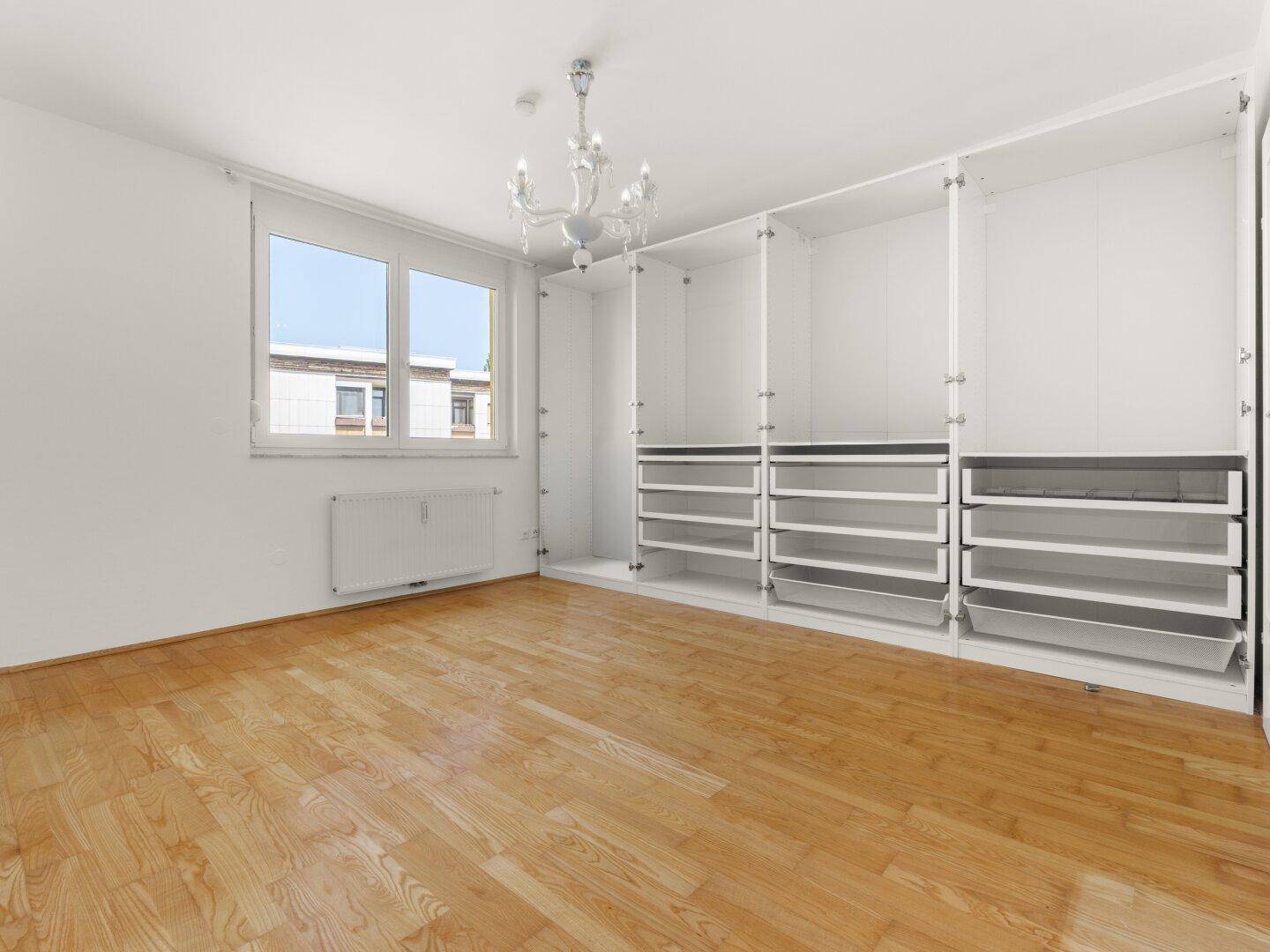 Geräumiges Schlafzimmer mit Parkettboden und praktischen, eingebauten Kleiderschränken.