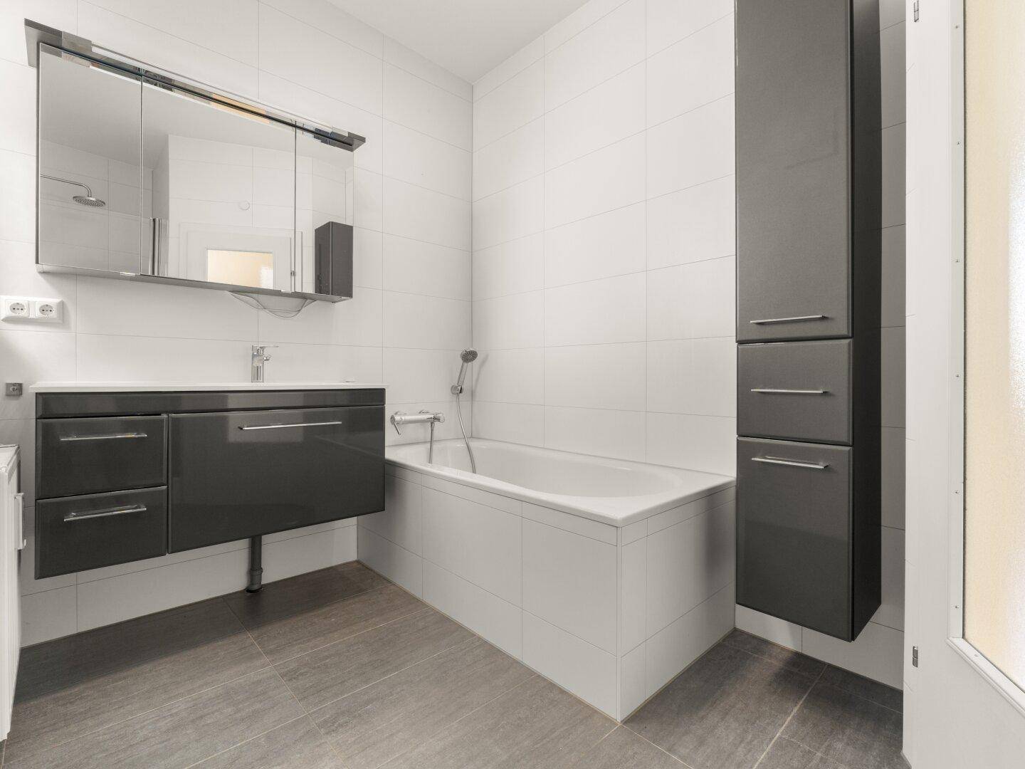Modernes Badezimmer mit Badewanne, elegantem Waschtisch und Spiegelschrank.