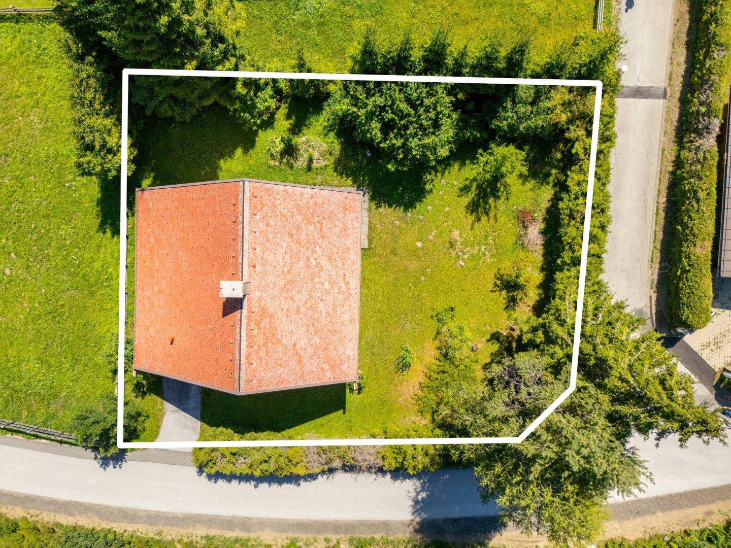 Draufsicht des Hauses mit Grundstücksgrenzen, umgeben von Bäumen und Wegen.