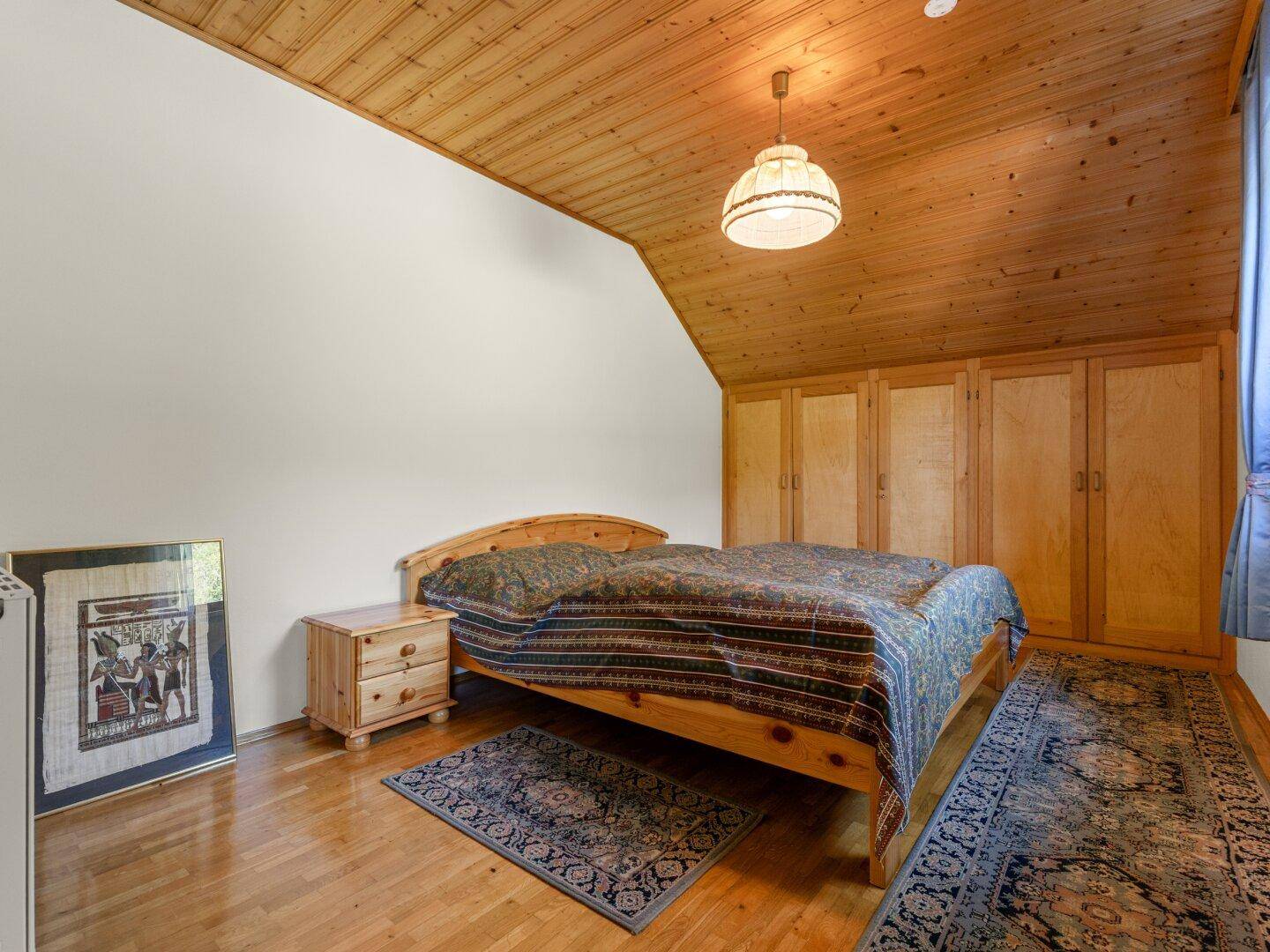 Gemütliches Schlafzimmer mit Holzbalkendecke, Einzelbett und traditionellen Teppichen.
