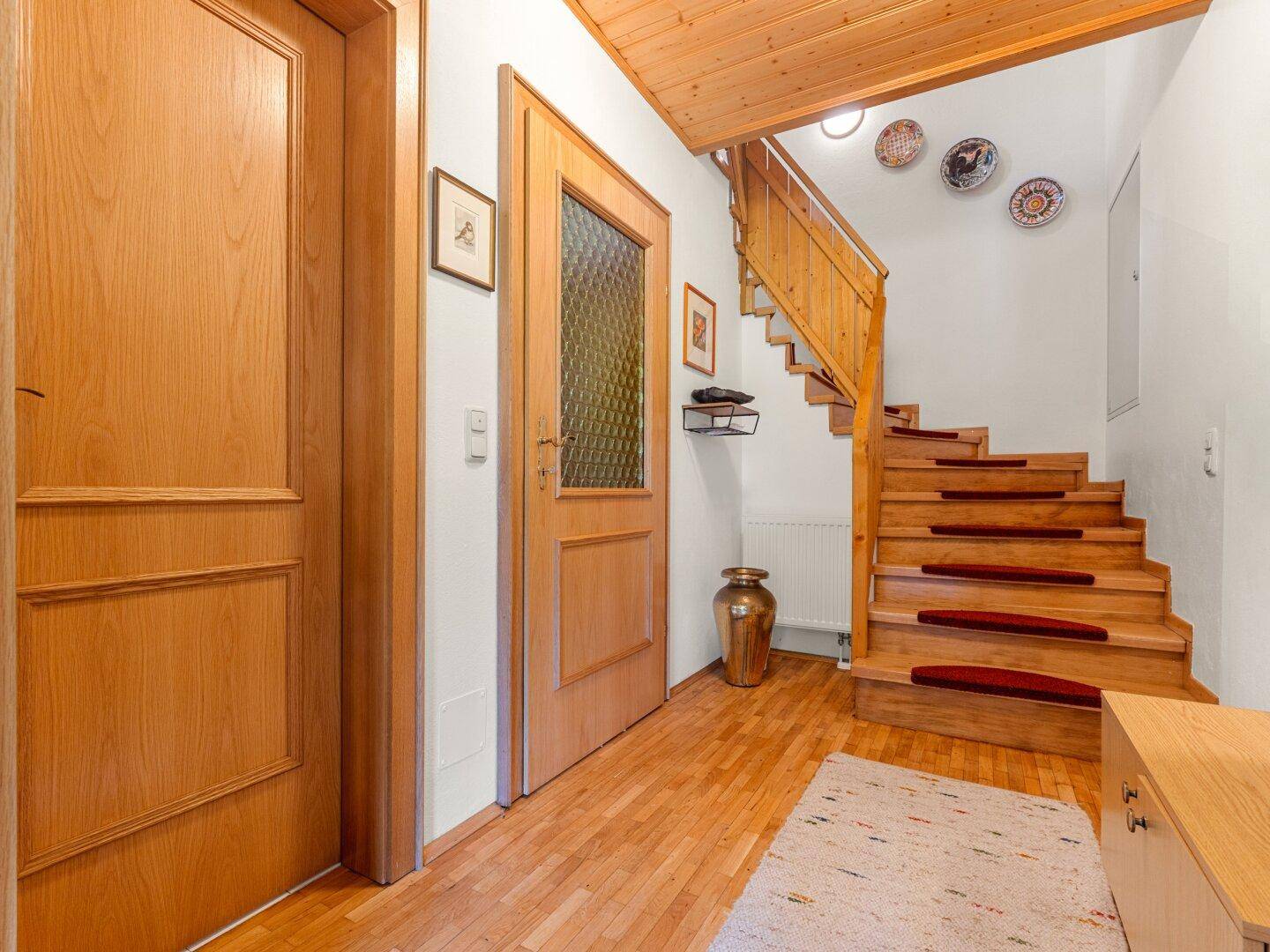 Heller Flur mit Holztreppe, Holzdecke und traditionellen Dekorationselementen.