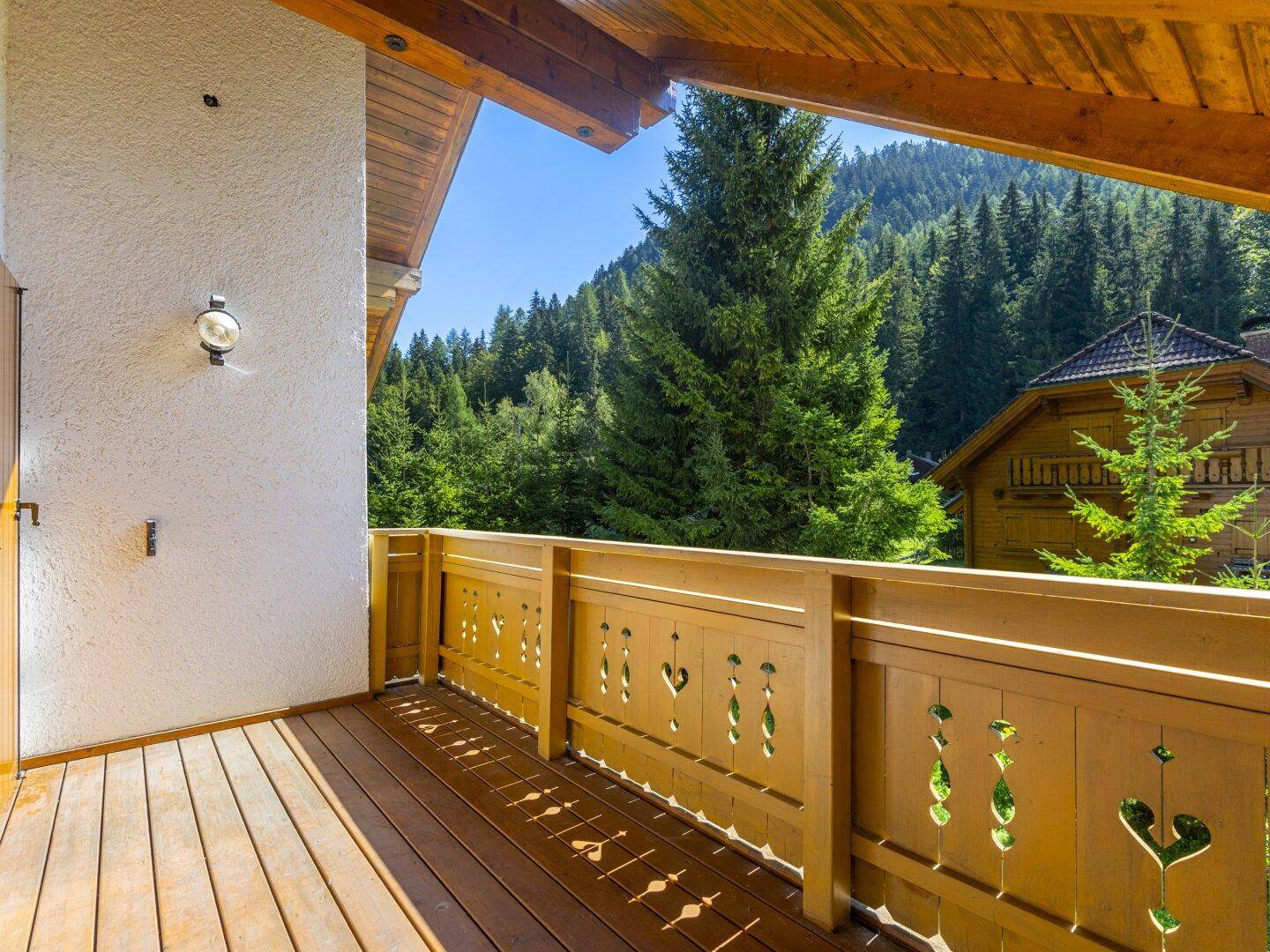 Traditioneller Holzbalkon mit geschnitztem Geländer und weitem Blick auf die Berge.