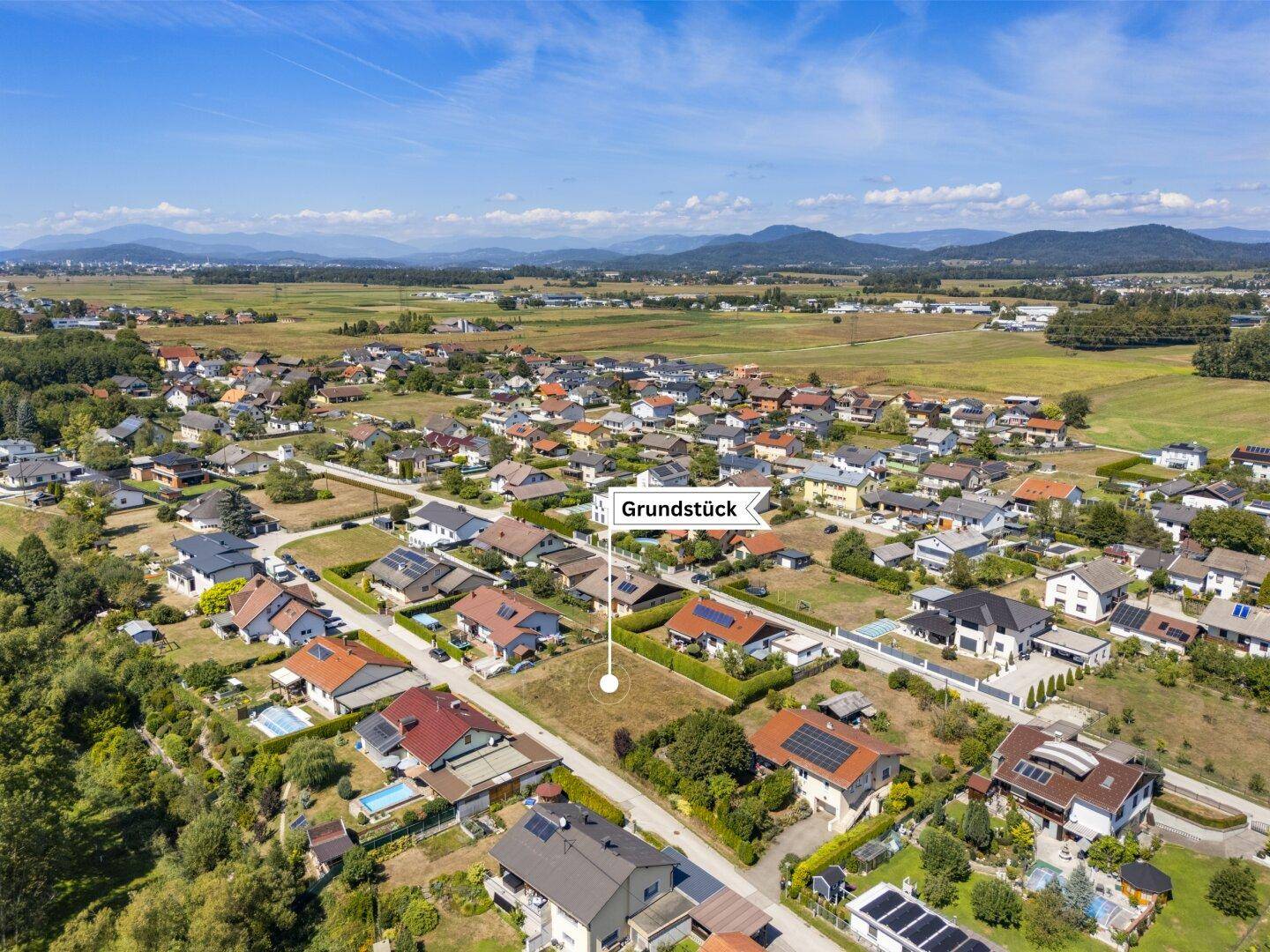 Weitwinkel-Luftaufnahme des Grundstücks mit Blick auf die umliegende Wohnsiedlung und weite Felder.