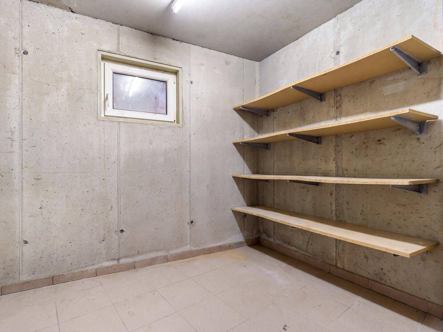Praktischer Abstellraum im Keller mit Regalen und kleinem Fenster, ideal für Lagerung.