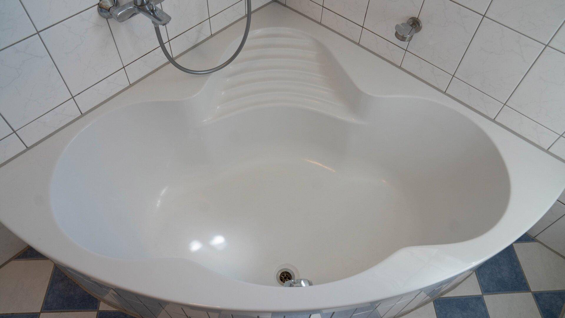 Detailansicht der geräumigen Eckbadewanne mit integrierter Sitzfläche im Badezimmer.