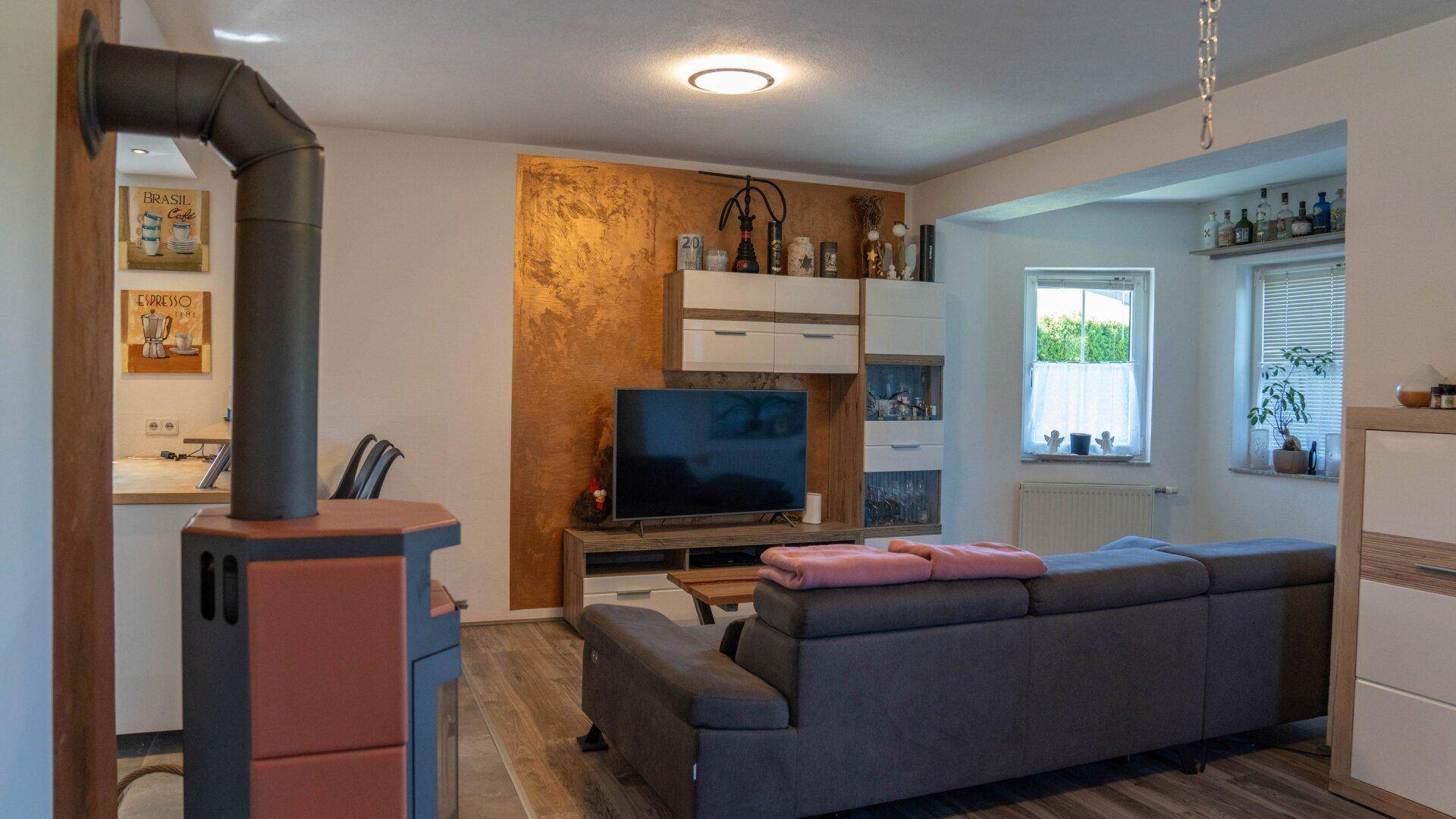 Wohnbereich mit modernem Holzofen, Fernseher und einer dekorativen Akzentwand.