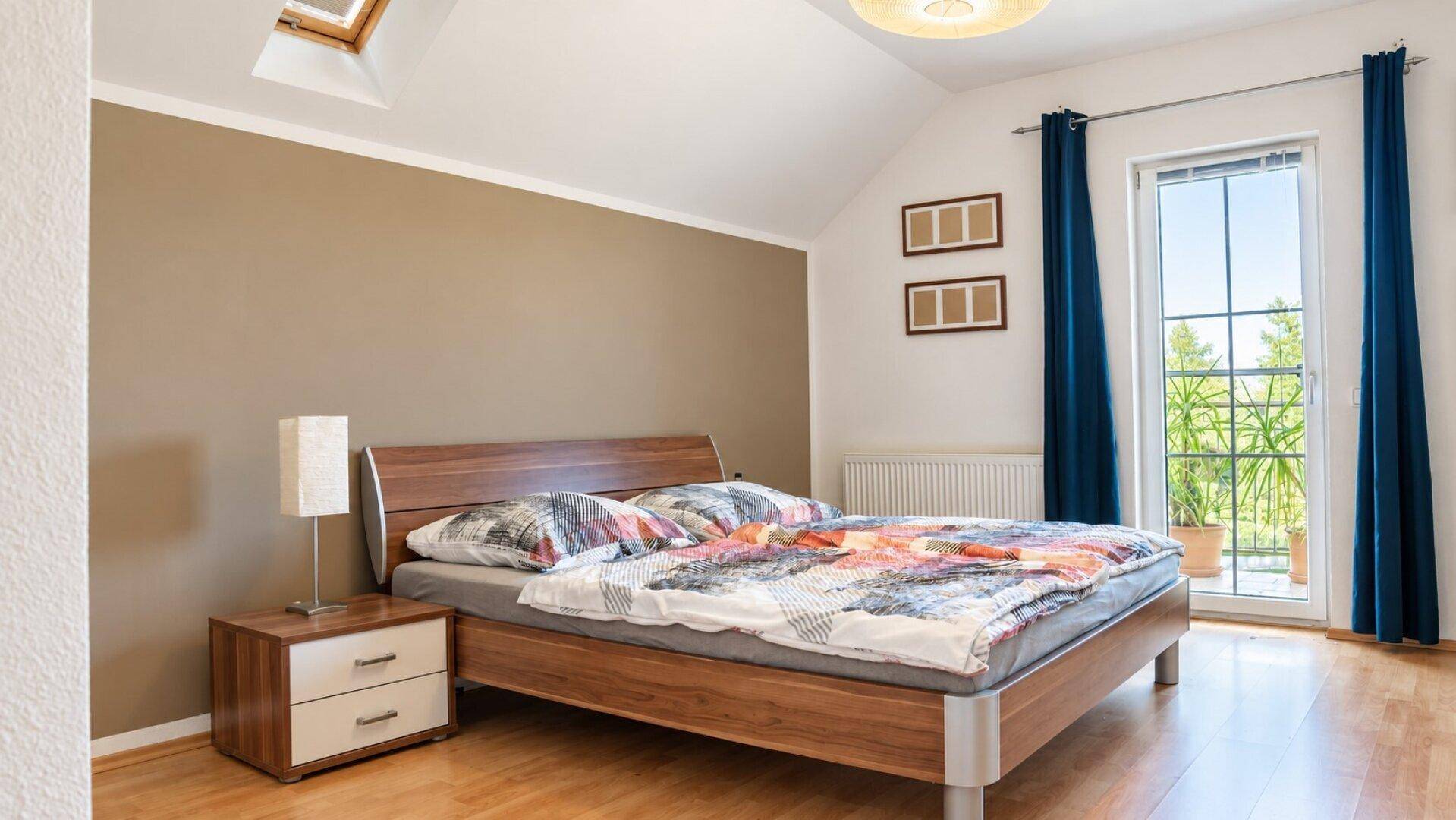 Gemütliches Schlafzimmer mit Holzbett, Parkettboden und Zugang zum Balkon.