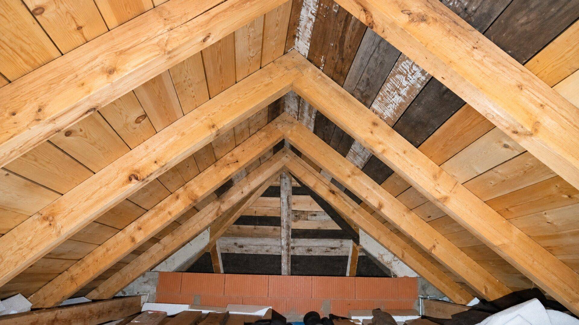 Dachboden mit sichtbaren Holzbalken und Holzverkleidung der Dachschräge.