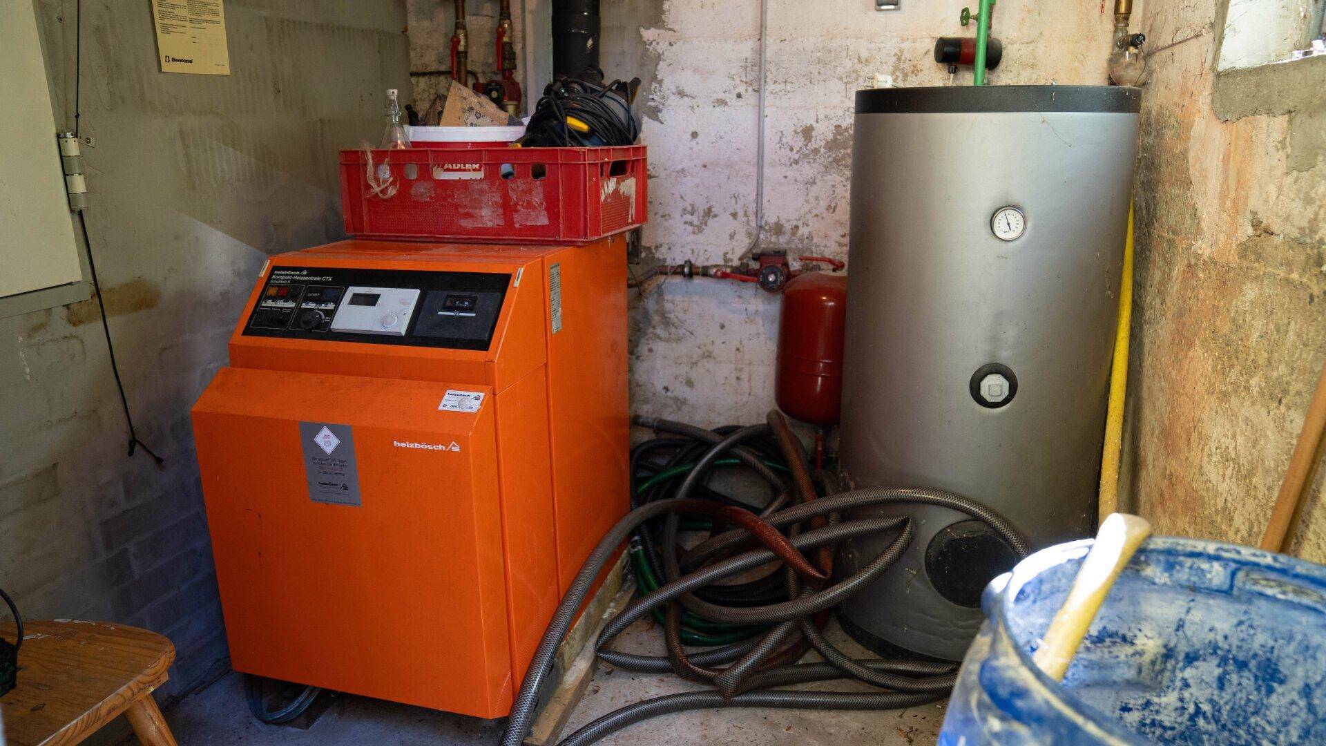 Heizungsraum im Keller mit Heizkessel, Warmwasserspeicher und Rohren.