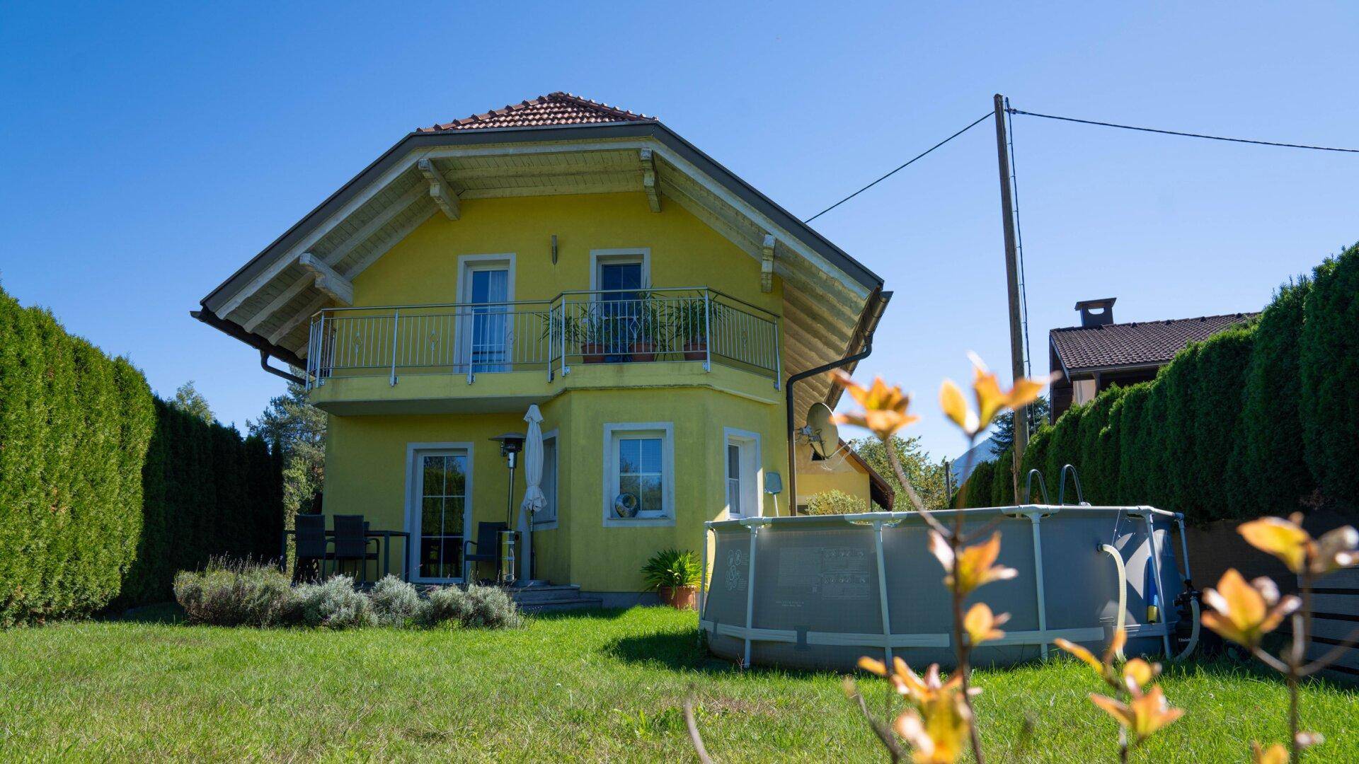 Freistehendes gelbes Haus mit Garten, Aufstellpool und Terrasse im Grünen.